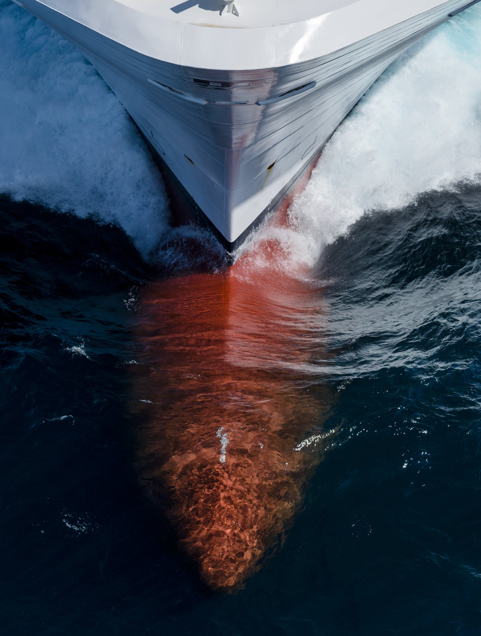 Fincantieri | Group - Business - Products - Cruise Ships - MSC Seaside: Aerial view of MSC Seaside cruise ship bow in operation, cutting through water creating foam, contrasting red hull visible beneath surface.