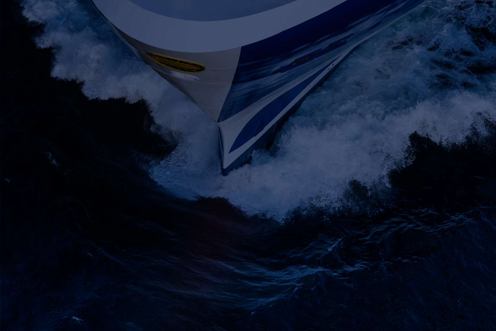 Fincantieri – Governance and Ethics: Background of a banner depicting the bow of a ship cutting through the water on a blue background. The image is very dark and low contrast, making it perfect for a background.