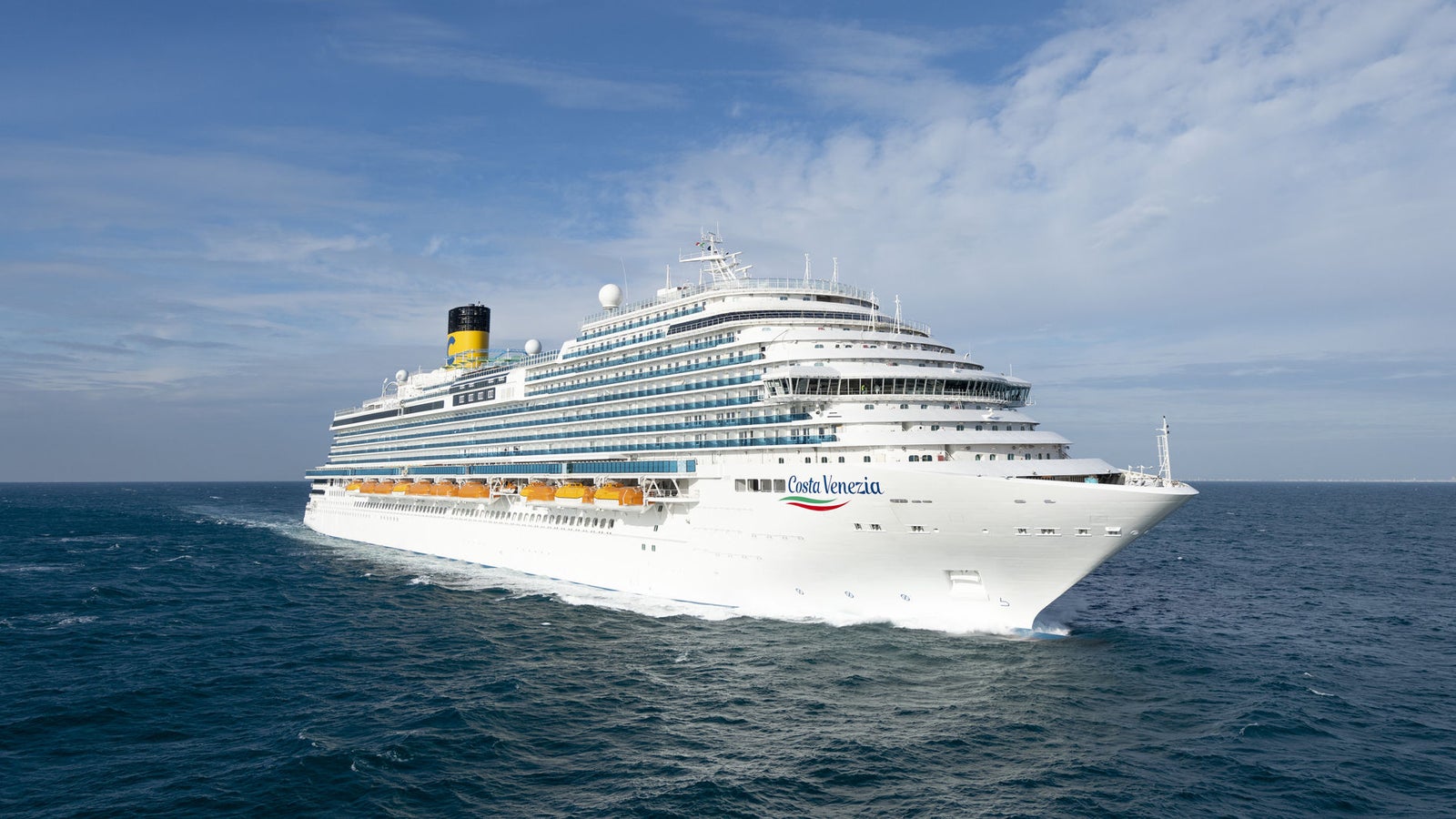 Fincantieri | Group - Business - Products - Cruise Ships - Costa Venezia: Large operational cruise ship with multiple decks, name 'Costa Venezia' clearly visible on hull, sailing on calm waters under clear sky, wide views of sea and sky emphasize serene maritime journey.