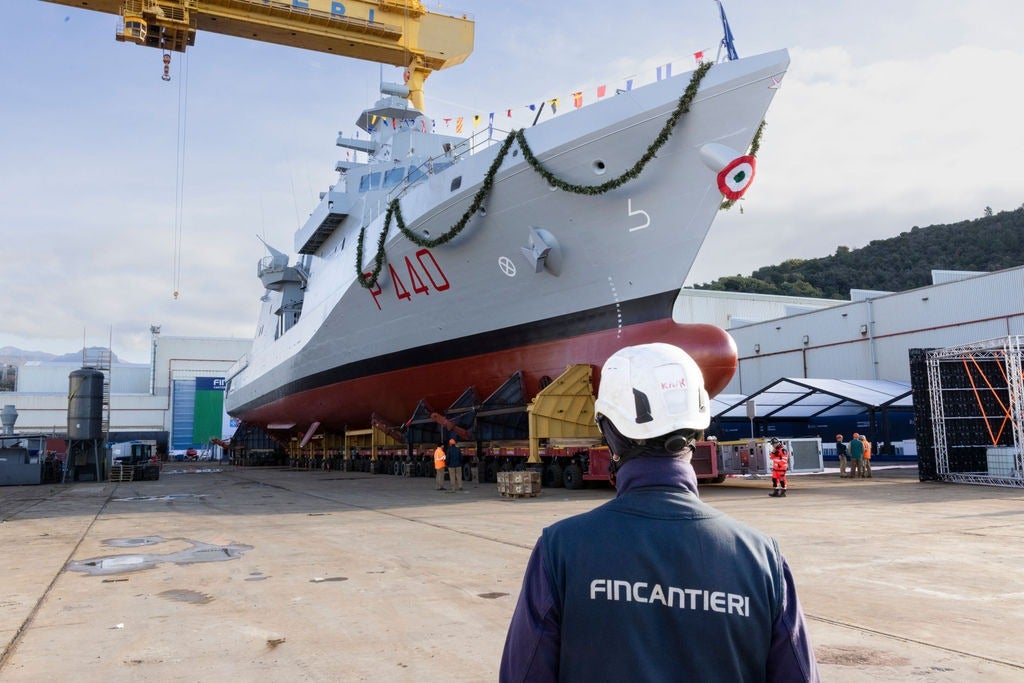 Newsroom - Press releases - 2026 - Fincantieri Group: launch of the first next-generation offshore patrol vessel for the Italian Navy: fincantieri worker in helmet observes offshore patrol vessel p440 decorated for launch at shipyard.