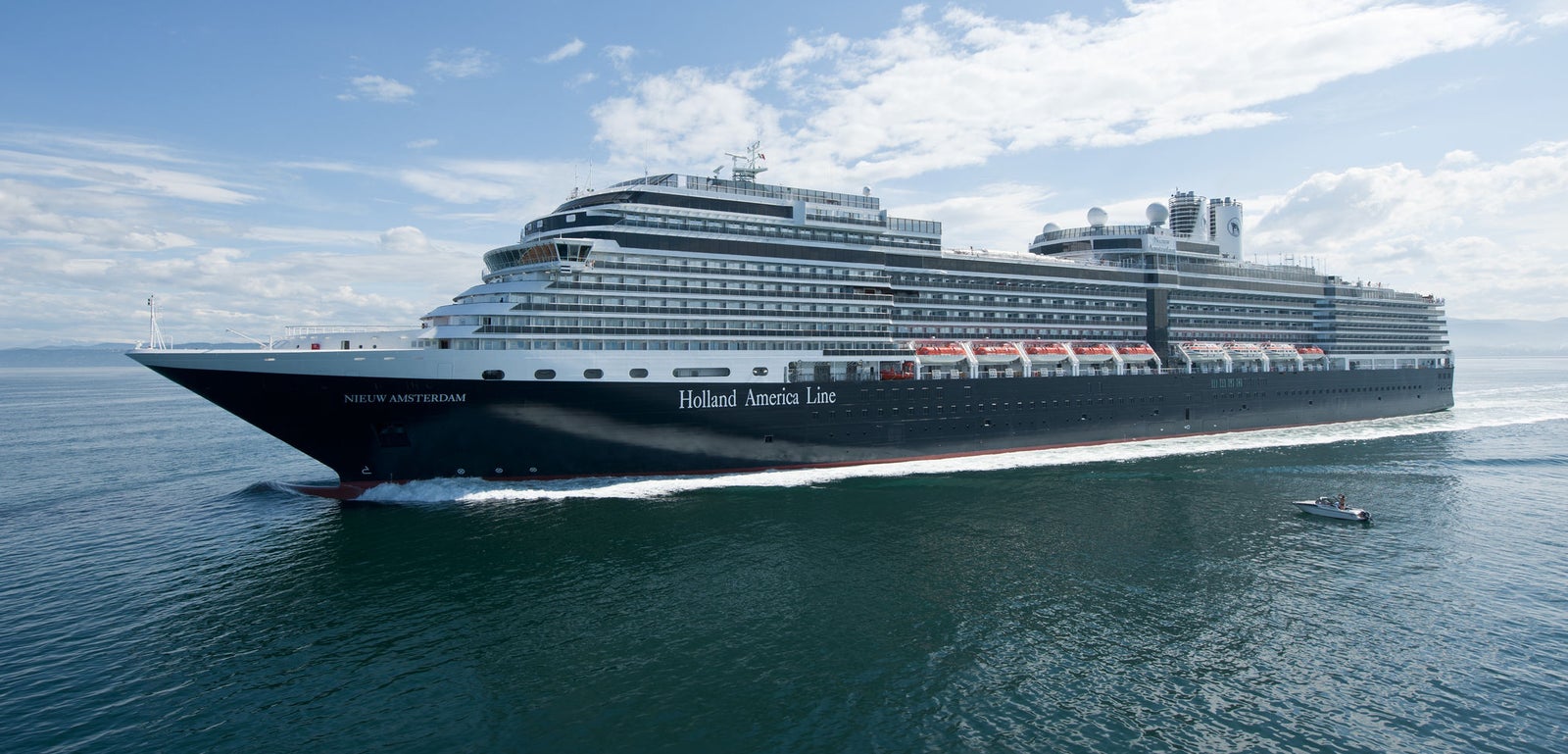 Fincantieri | Group - Business - Products - Cruise Ships - Nieuw Amsterdam: Large Holland America Line cruise ship in operation sailing on calm waters under partly cloudy sky, multiple decks, lifeboats, elegant white and black exterior, small boat visible nearby highlighting ship’s size.