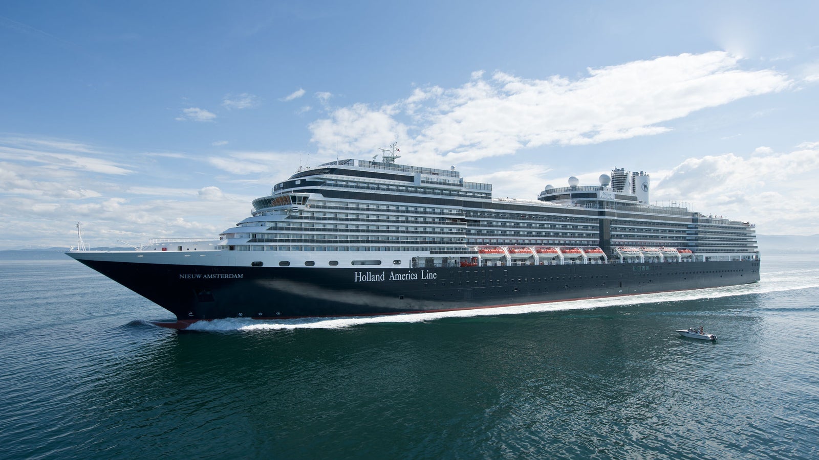 Fincantieri | Group - Business - Products - Cruise Ships - Nieuw Amsterdam: Large Holland America Line cruise ship in operation sailing on calm waters under partly cloudy sky, multiple decks, lifeboats, elegant white and black exterior, small boat visible nearby highlighting ship’s size.