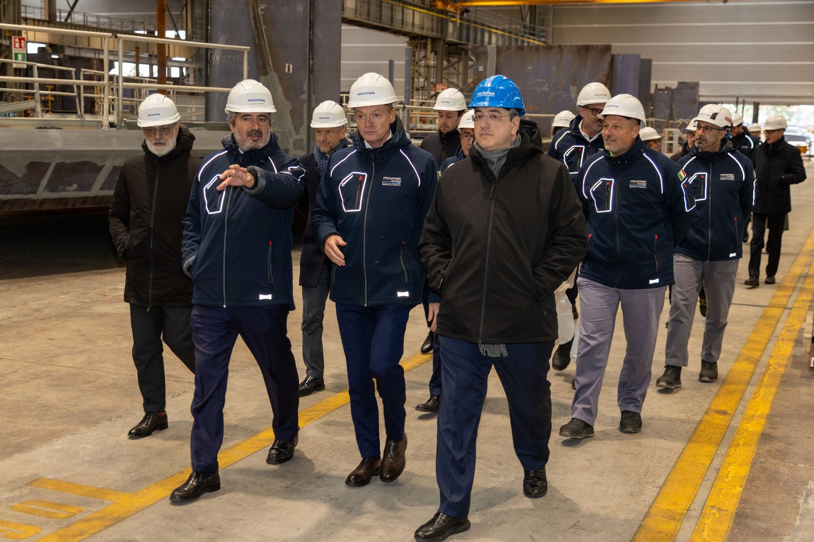 Newsroom - Comunicati stampa - 2025 - Gruppo Fincantieri: Fincantieri: visita del Commissario Europeo Apostolos Tzitzikostas al cantiere di Monfalcone: Il Commissario Europeo Apostolos Tzitzikostas visita il cantiere navale di Monfalcone accompagnato da tecnici e manager Fincantieri, tutti con caschi di sicurezza e abbigliamento aziendale, all’interno dei reparti produttivi.