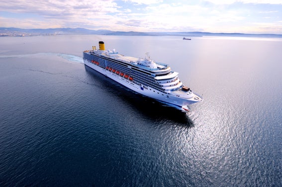 Fincantieri | Gruppo - Business - Prodotti - Navi da Crociera - Costa Luminosa: Grande nave da crociera operativa con molti ponti e scialuppe di salvataggio visibili lungo i lati, scivola su acque calme sotto cielo luminoso, design elegante e moderno.