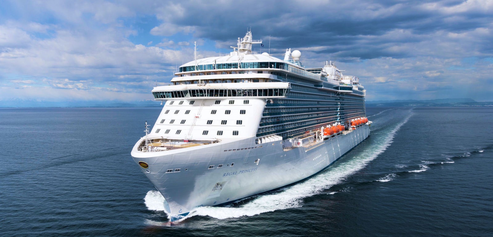 Fincantieri | Group - Business - Products - Cruise Ships - Regal Princess: Large modern operational cruise ship sailing on calm ocean waters under partly cloudy sky, multiple decks and visible lifeboats along sides.