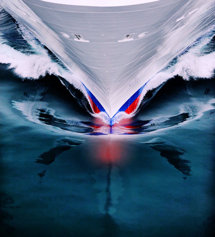 Fincantieri | Group - Business - Products - Cruise Ships - Costa Deliziosa: Close-up of Costa Deliziosa cruise ship bow in operation cutting through water, visible red and blue hull details.
