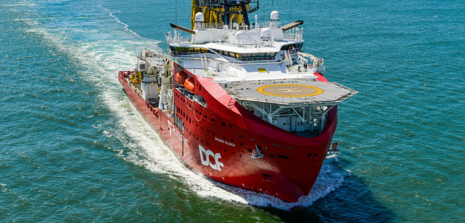 Prodotto - Offshore Support Vessel Skandi Onlinda: Vista laterale della nave operativa in navigazione, scafo rosso, elisuperficie e attrezzature industriali come gru e macchinari visibili, logo DOF ben evidente sullo scafo.
