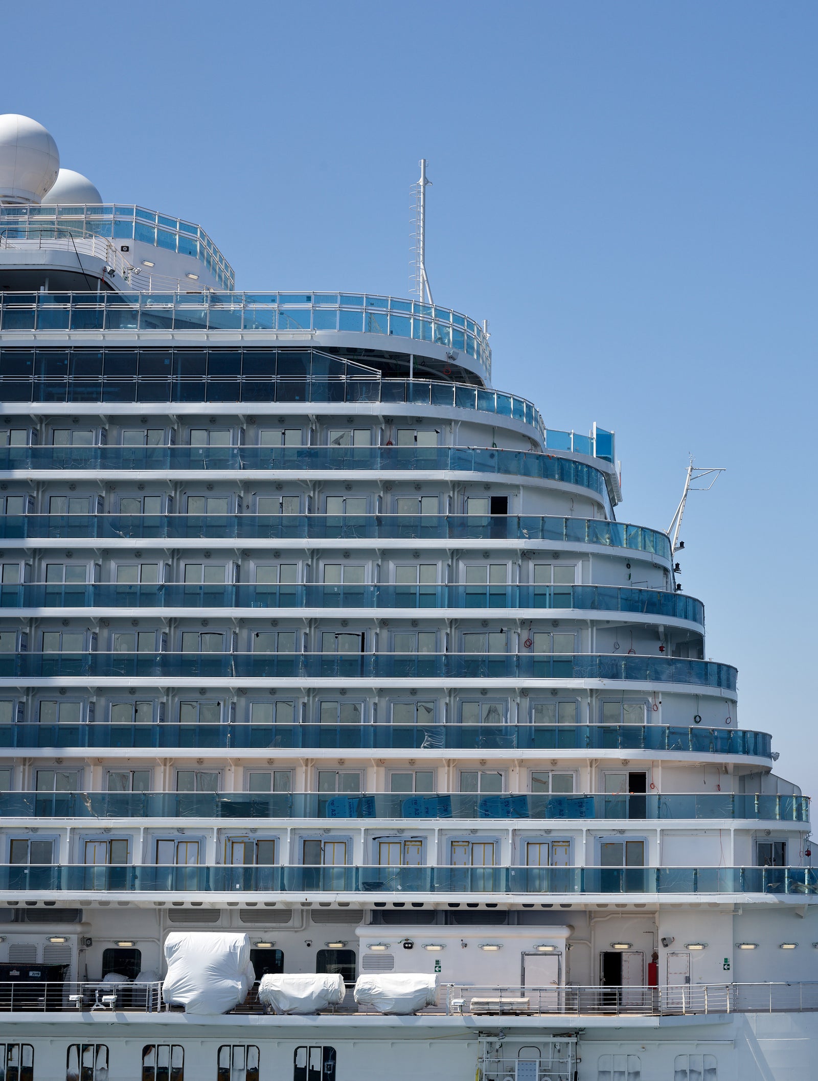 Fincantieri | Group - Business - Products - Cruise Ships - Enchanted Princess: Large operational cruise ship with multiple decks, numerous balconies and modern architectural design, sailing on calm open waters under clear blue sky, serene ocean and minimalist background highlight the ship’s grandeur.