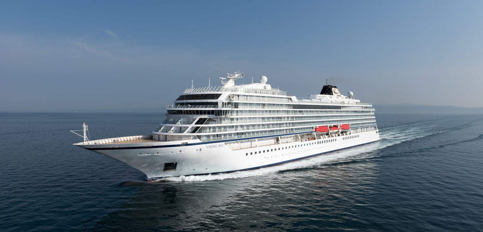 Fincantieri | Group - Business - Products - Cruise Ships - Viking Sky: Side view of Viking Sky cruise ship in operation navigating open sea, white hull, multiple passenger decks, visible lifeboats along sides under clear sky.