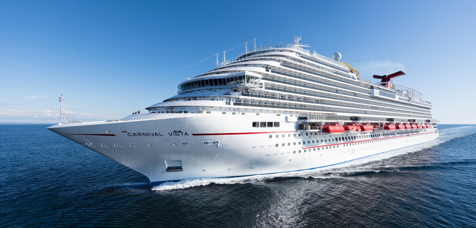 incantieri | Group - Business - Products - Cruise Ships - Carnival Vista: Carnival Vista cruise ship in operation, sailing on calm open waters under serene blue sky, 'Carnival Vista' name clearly visible on hull, vibrant red lifeboats and elegant white exterior highlight modern design, tranquil ocean environment emphasizes leisure and travel.