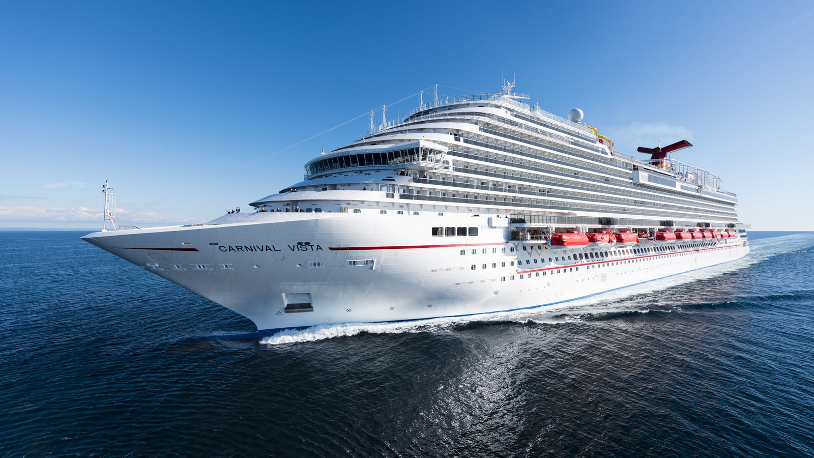 incantieri | Group - Business - Products - Cruise Ships - Carnival Vista: Carnival Vista cruise ship in operation, sailing on calm open waters under serene blue sky, 'Carnival Vista' name clearly visible on hull, vibrant red lifeboats and elegant white exterior highlight modern design, tranquil ocean environment emphasizes leisure and travel.