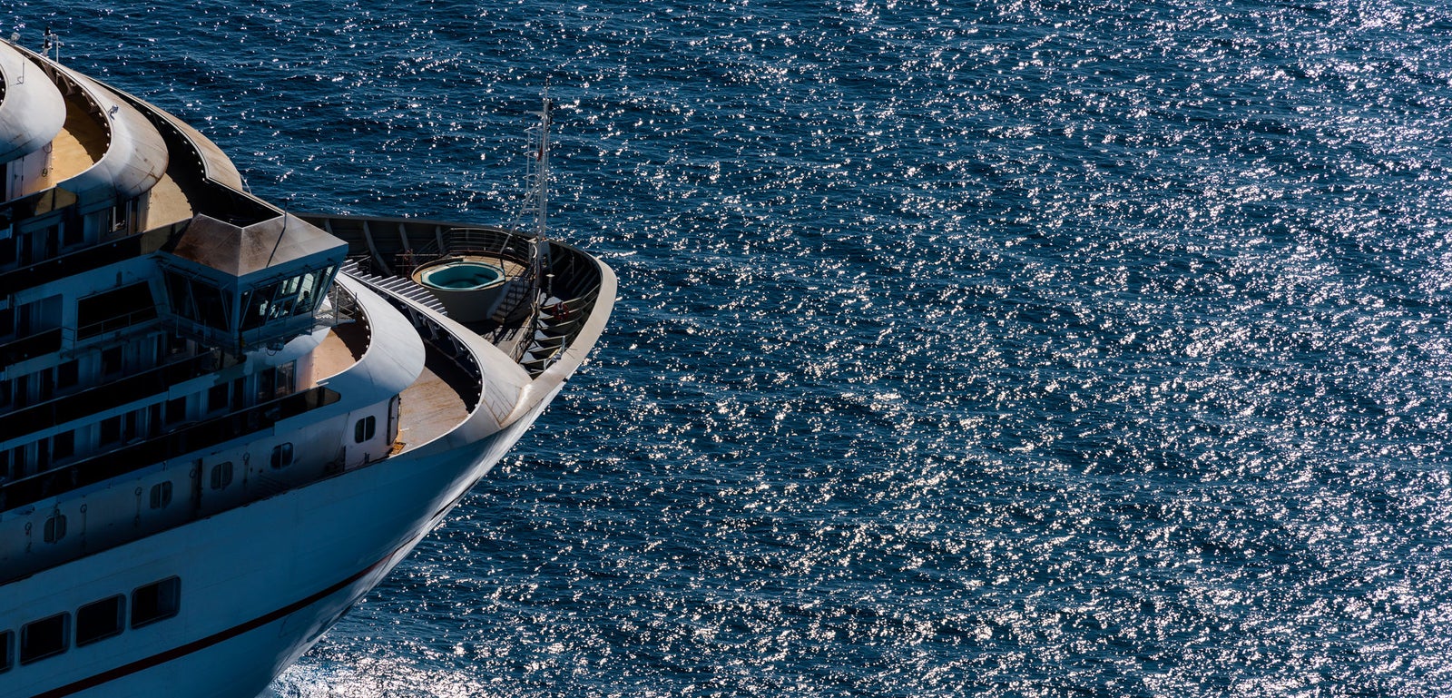 Fincantieri | Group - Business - Products - Cruise Ships - Carnival Horizon: Bow of operational luxury cruise ship gliding on sparkling blue ocean waters, multiple decks and visible pool area, sunlight reflecting on water, vibrant and serene maritime scene.