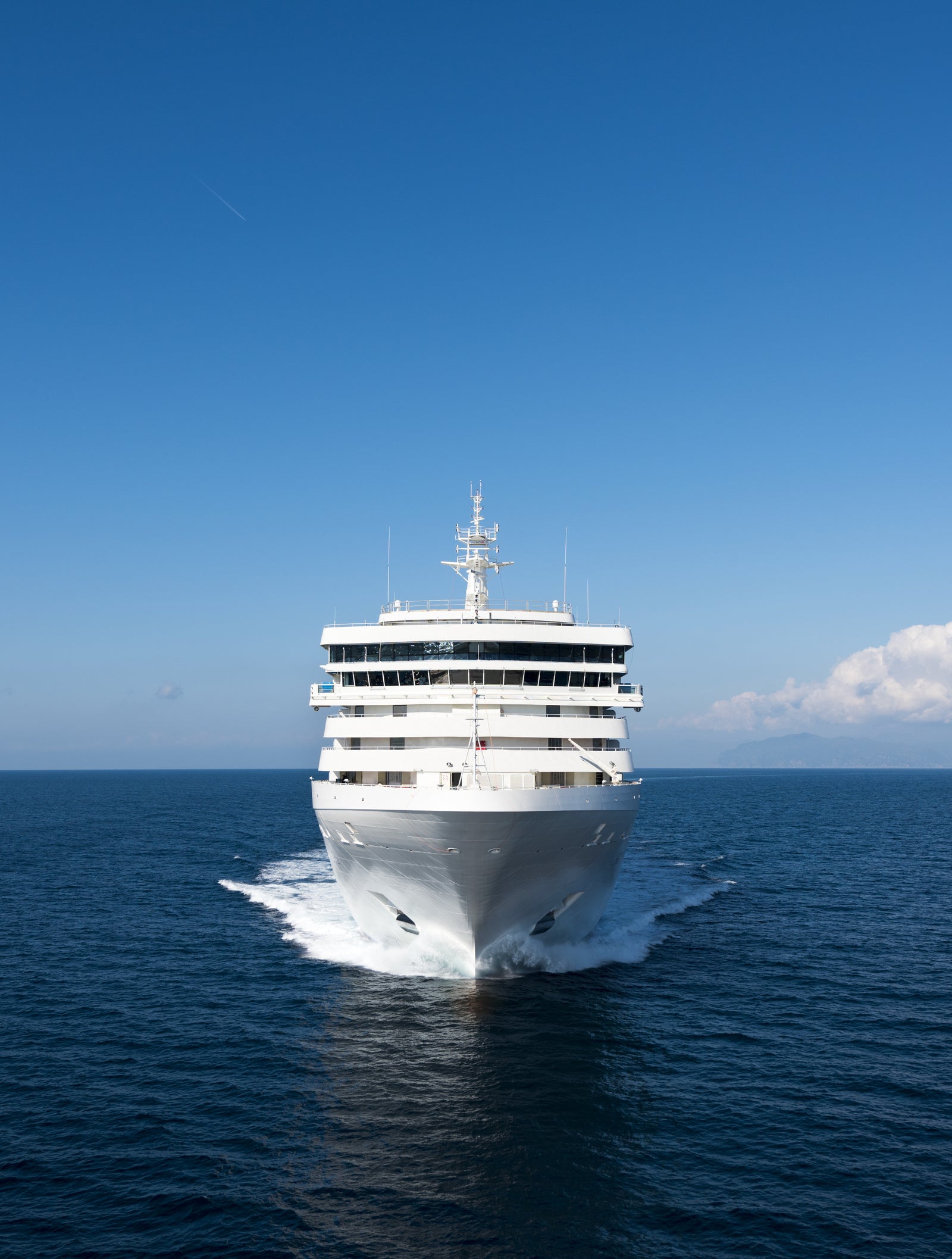 Fincantieri | Group - Business - Products - Cruise Ships - Silver Spirit: Large luxury operational white cruise ship gliding on calm waters under clear sky, multiple decks with balconies and relaxation spaces, visible lifeboats.