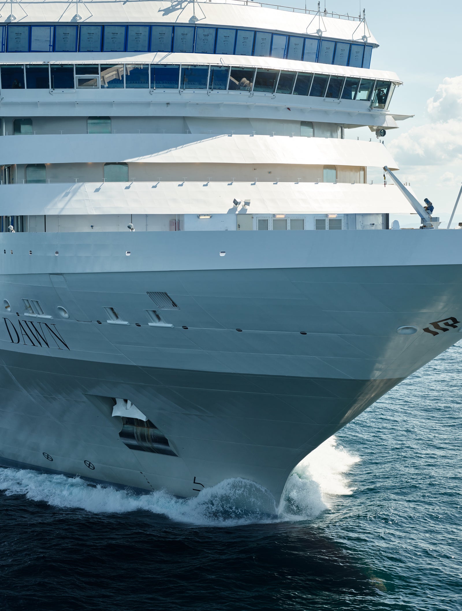 Fincantieri | Group - Business - Products - Cruise Ships - Silver Dawn: Large luxury cruise ship in operation gliding through open ocean under clear blue sky, multiple decks and modern design details, name 'Silver Dawn' clearly visible on hull, calm waters and bright daylight enhance the serene majestic atmosphere.