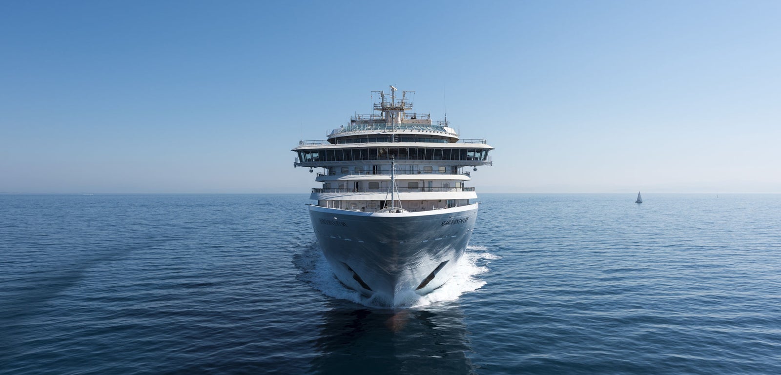 Fincantieri | Gruppo - Business - Prodotti - Navi da Crociera - Seabourn Encore: Vista frontale della nave Seabourn Encore operativa in navigazione su mare aperto, barca a vela visibile a distanza per confronto di scala.