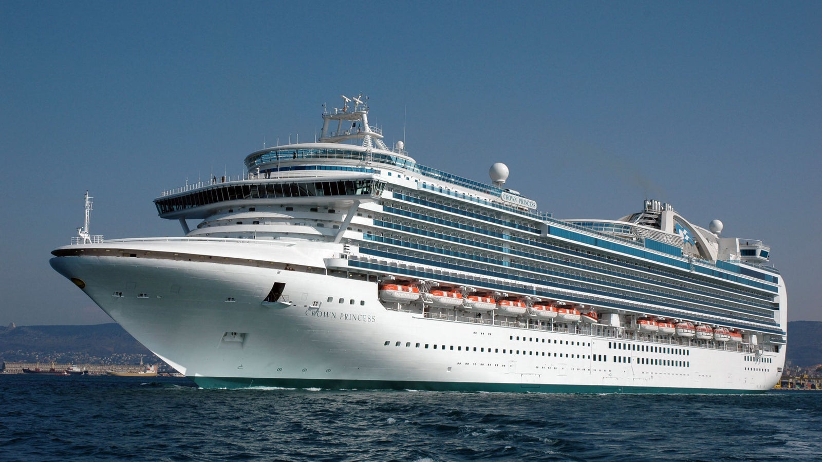 Fincantieri | Group - Business - Products - Cruise Ships - Crown Princess: Side view of the white Crown Princess cruise ship in operation, multiple decks and visible lifeboats, sleek design, Crown Princess name on hull.