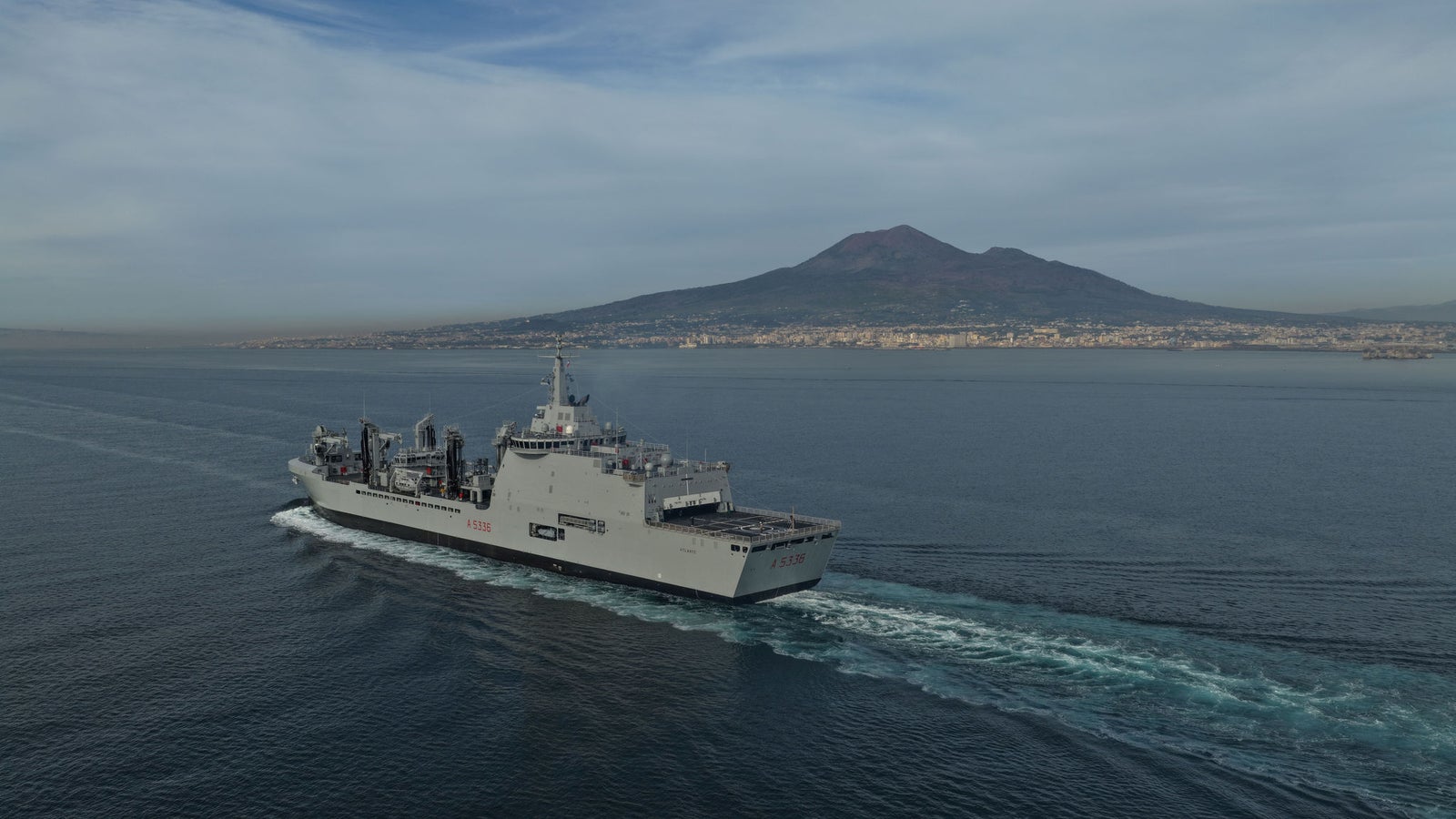 newsroom - press releases - 2025 - fincantieri group: fincantieri delivers "atlante", second lss unit for the italian navy: lss "atlante" military support vessel sailing near naples, aerial view with mount vesuvius and city skyline in the background.
