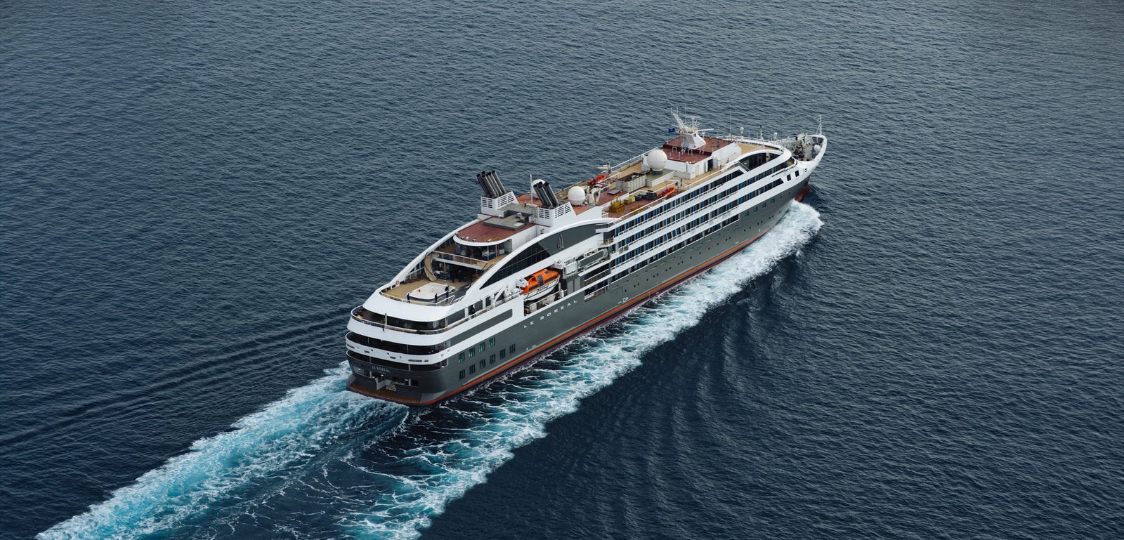  Fincantieri | Group - Business - Products - Cruise Ships - Le Boreal: Modern luxury cruise ship in operation navigating calm deep blue ocean waters, multiple decks, outdoor seating areas, sleek design elements, serene maritime journey with clear skies and gentle waves, no visible text or numeric values on ship.