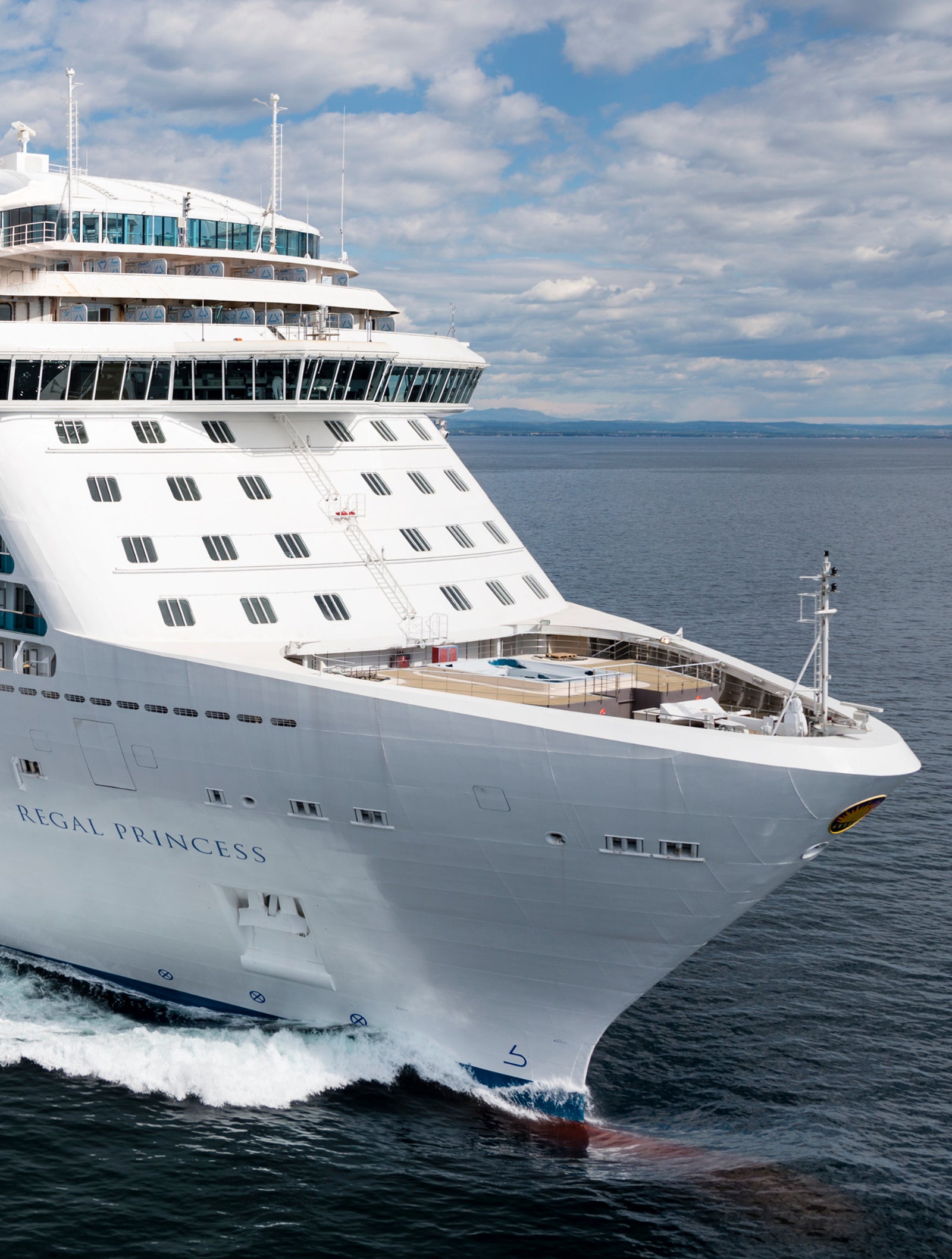 Fincantieri | Group - Business - Products - Cruise Ships - Regal Princess: Large operational white cruise ship gliding on calm ocean waters, visible wake behind, partly cloudy sky with patches of blue.