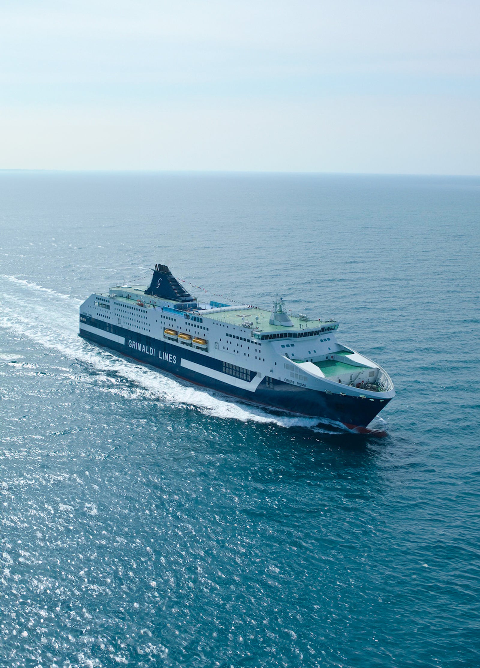 Fincantieri | Gruppo - Sostenibilità - Eccellenza industriale - Cilenti: Grande traghetto ‘Grimaldi Lines’ operativo in navigazione su mare calmo sotto cielo sereno, esterno bianco e blu con ponti e finestre passeggeri visibili; ambiente marittimo evidenzia movimento e dimensioni della nave.