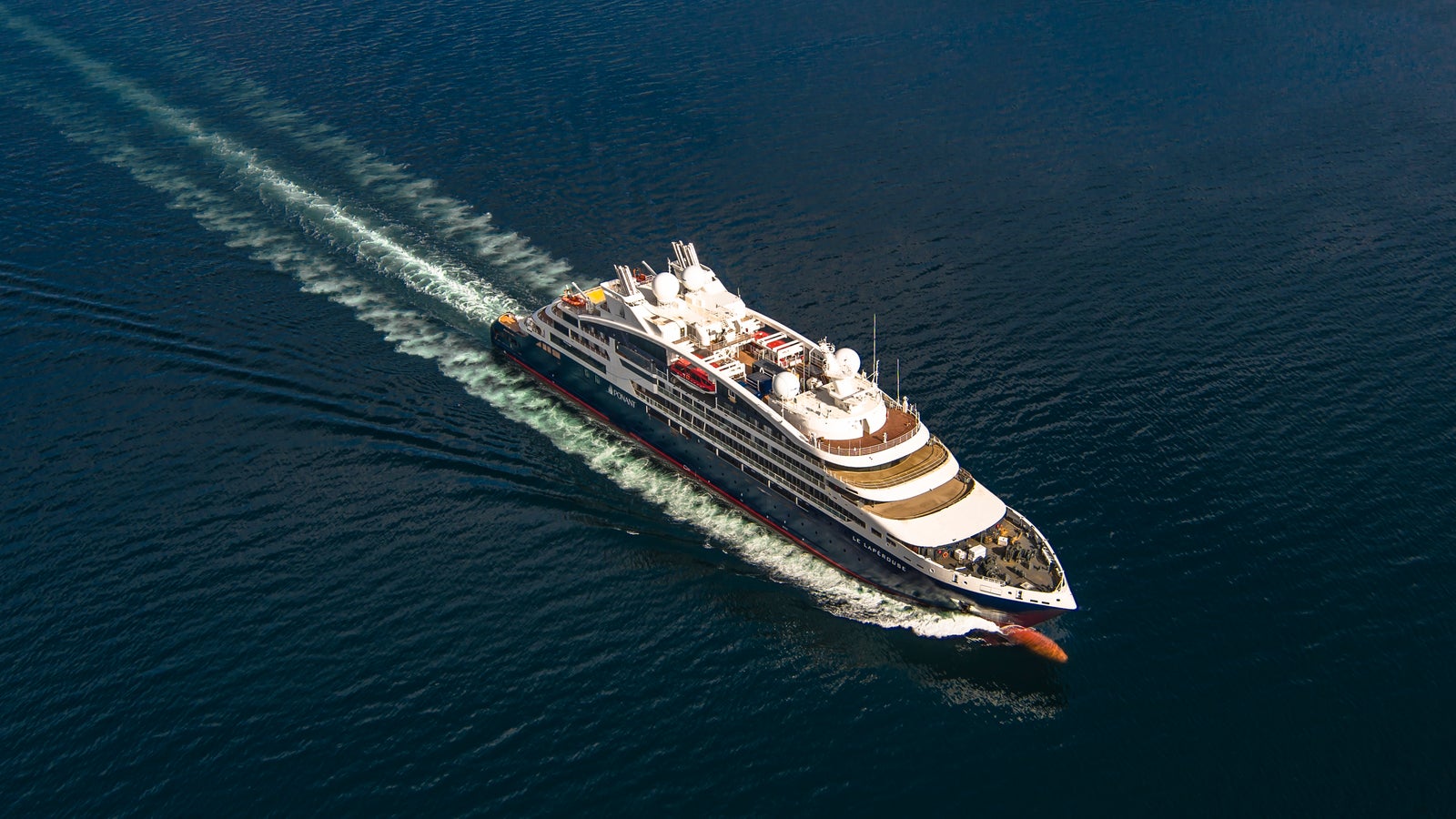 Fincantieri | Gruppo - Business - Prodotti - Navi da Crociera - Le Lapérouse: Vista aerea della nave Le Lapérouse operativa in navigazione su mare aperto, scafo dal profilo lineare, ponti passeggeri multipli, scia visibile in acqua.