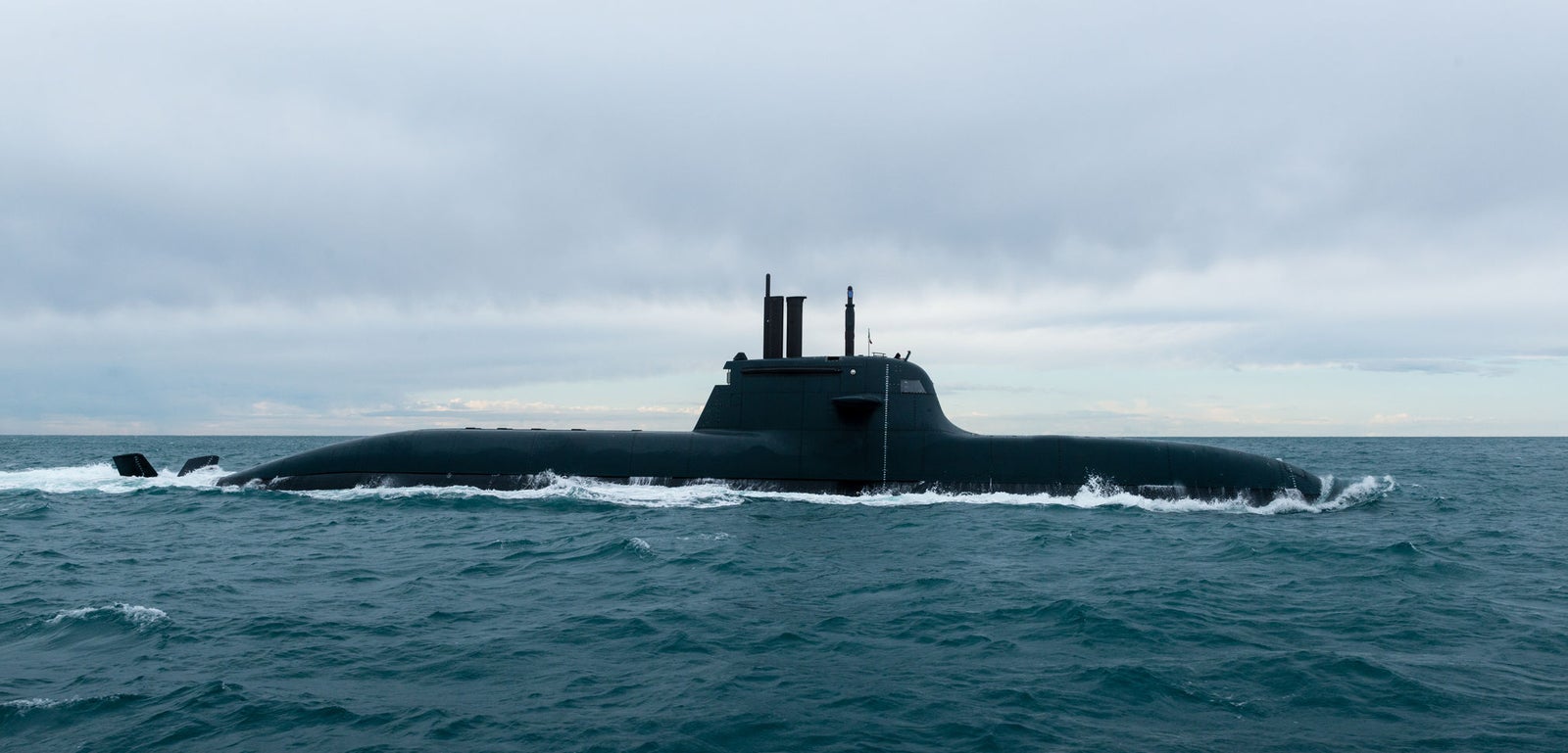 Fincantieri | Gruppo - Business - Prodotti - Sommergibili - Classe Todaro: Sommergibile nero slanciato operativo, in navigazione sulla superficie dell’oceano aperto, torre di comando e periscopi visibili, onde calme, cielo nuvoloso.