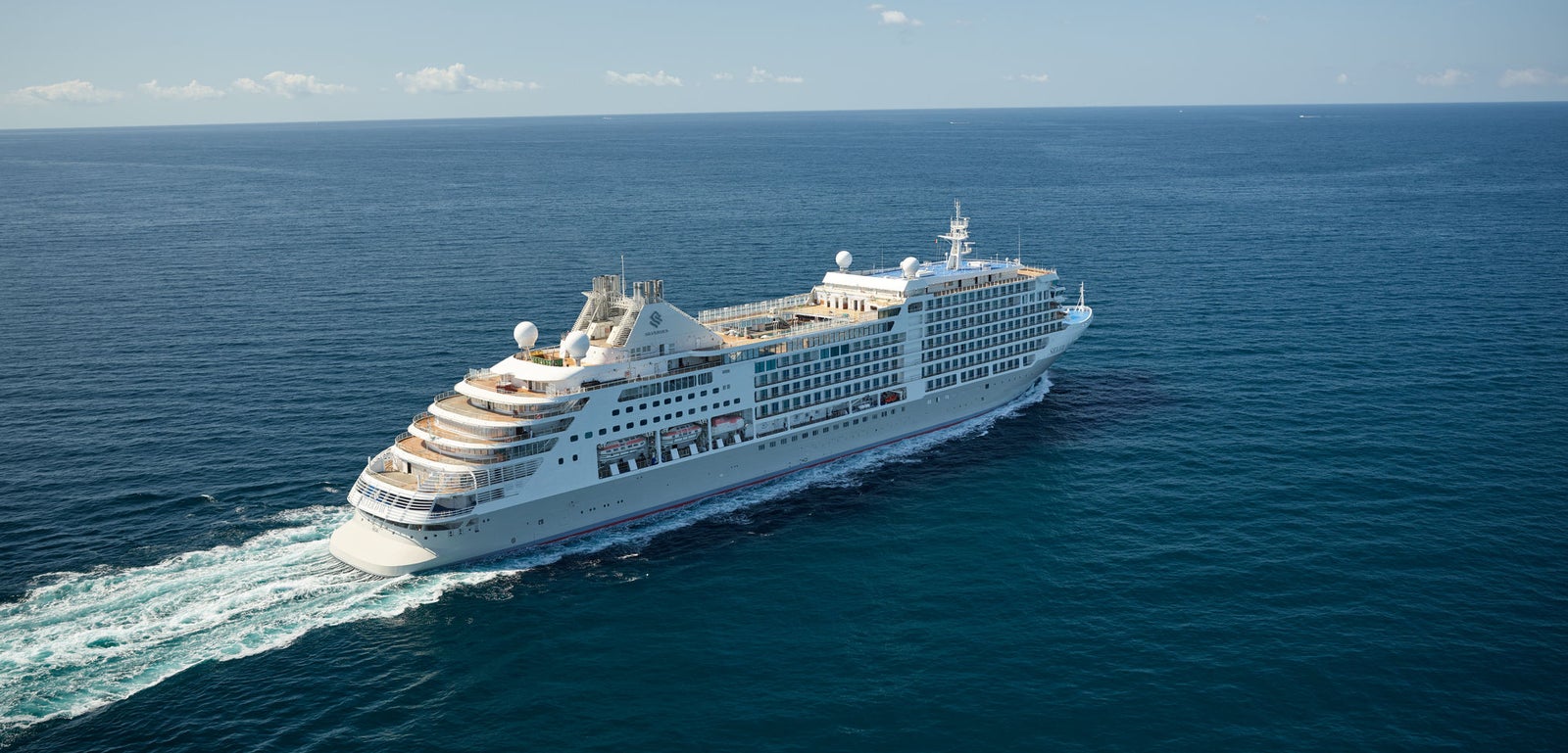  Fincantieri | Group - Business - Products - Cruise Ships - Silver Dawn: Large white luxury cruise ship in operation navigating calm deep blue ocean waters under clear sky, multiple decks and visible amenities, setting highlights sea vastness and journey tranquility.