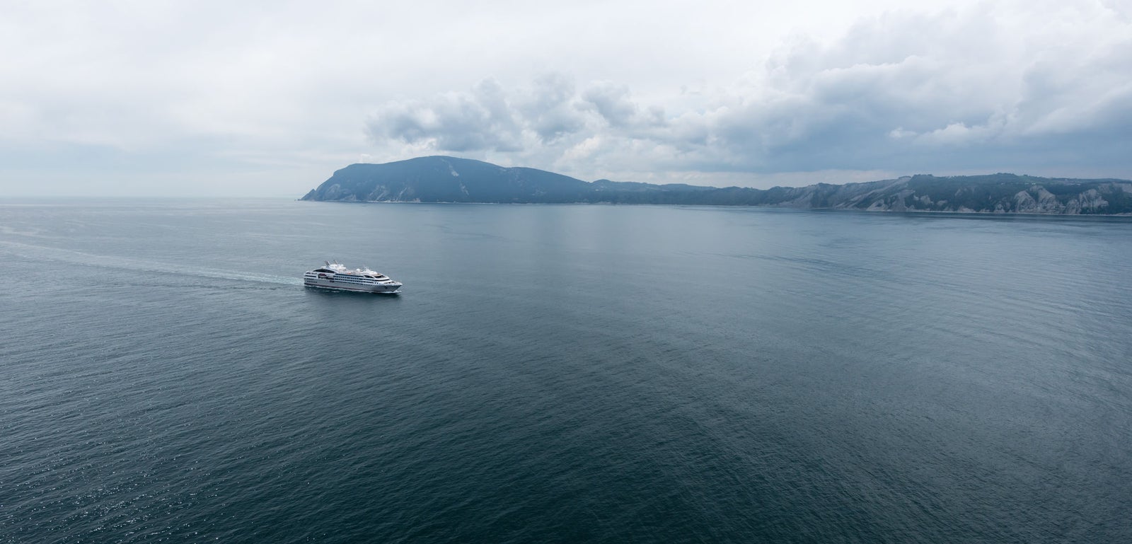 Fincantieri | Group - Business - Products - Cruise Ships - Le Soléal: Side view of Le Soléal cruise ship in operation navigating open sea, white hull, multiple passenger decks, visible lifeboats along sides, clear sky.