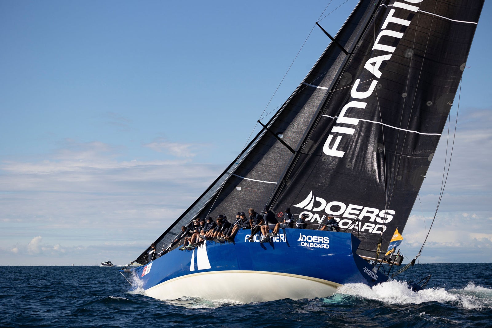Crewed racing sailboat cutting through waves