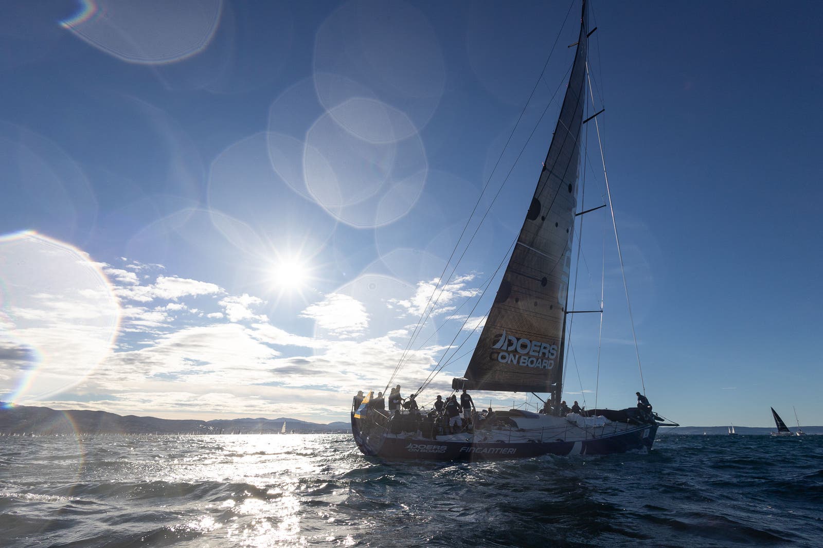 Sailboat racing across sunlit open sea