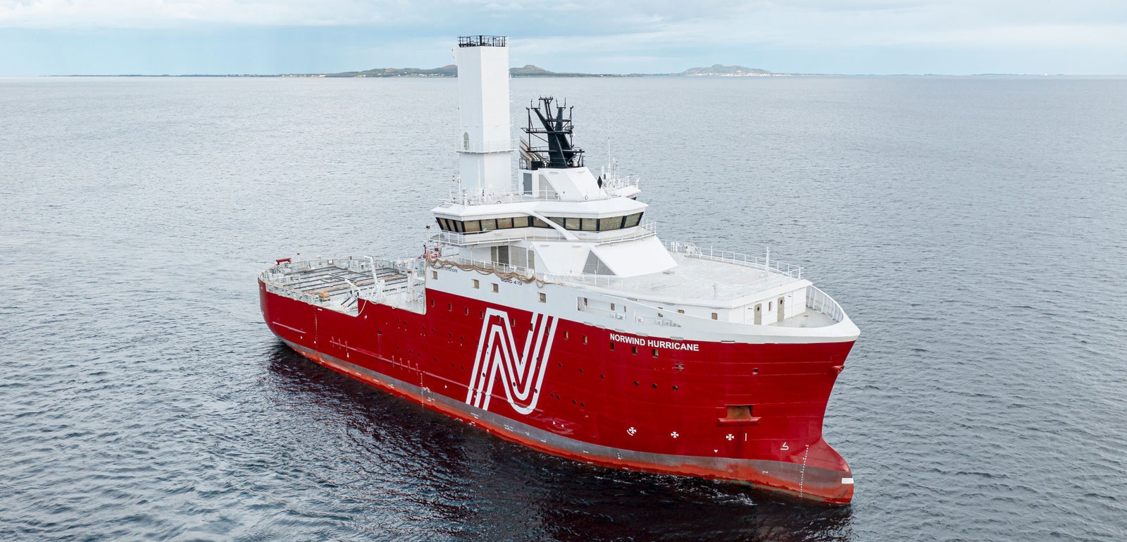 Prodotto - Offshore Support Vessel Norwind Hurricane: Vista laterale della nave operativa in navigazione, scafo rosso con logo N bianco, struttura centrale alta, equipaggiamenti di coperta visibili, design moderno.