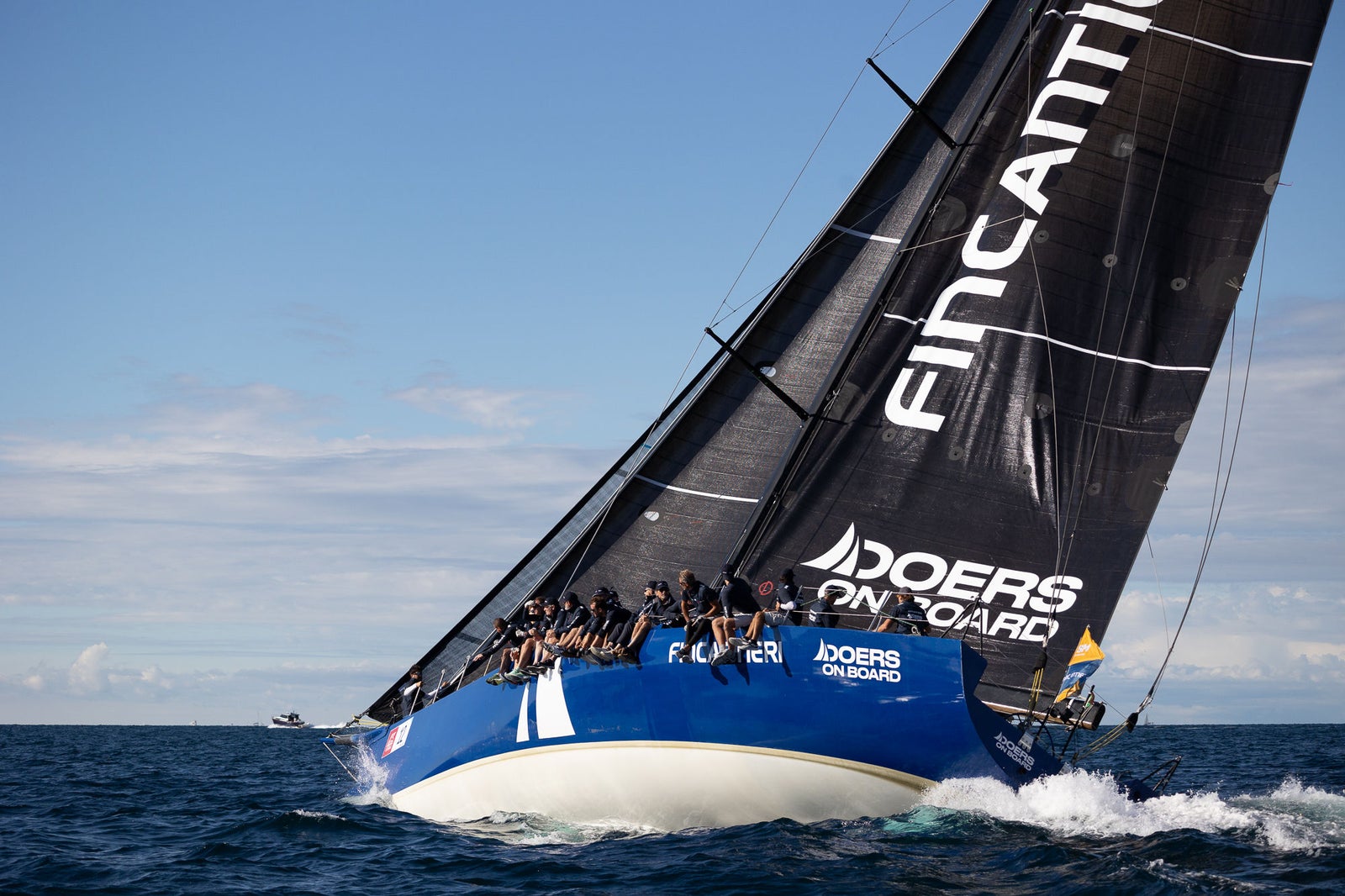 Racing sailboat crew cutting through waves