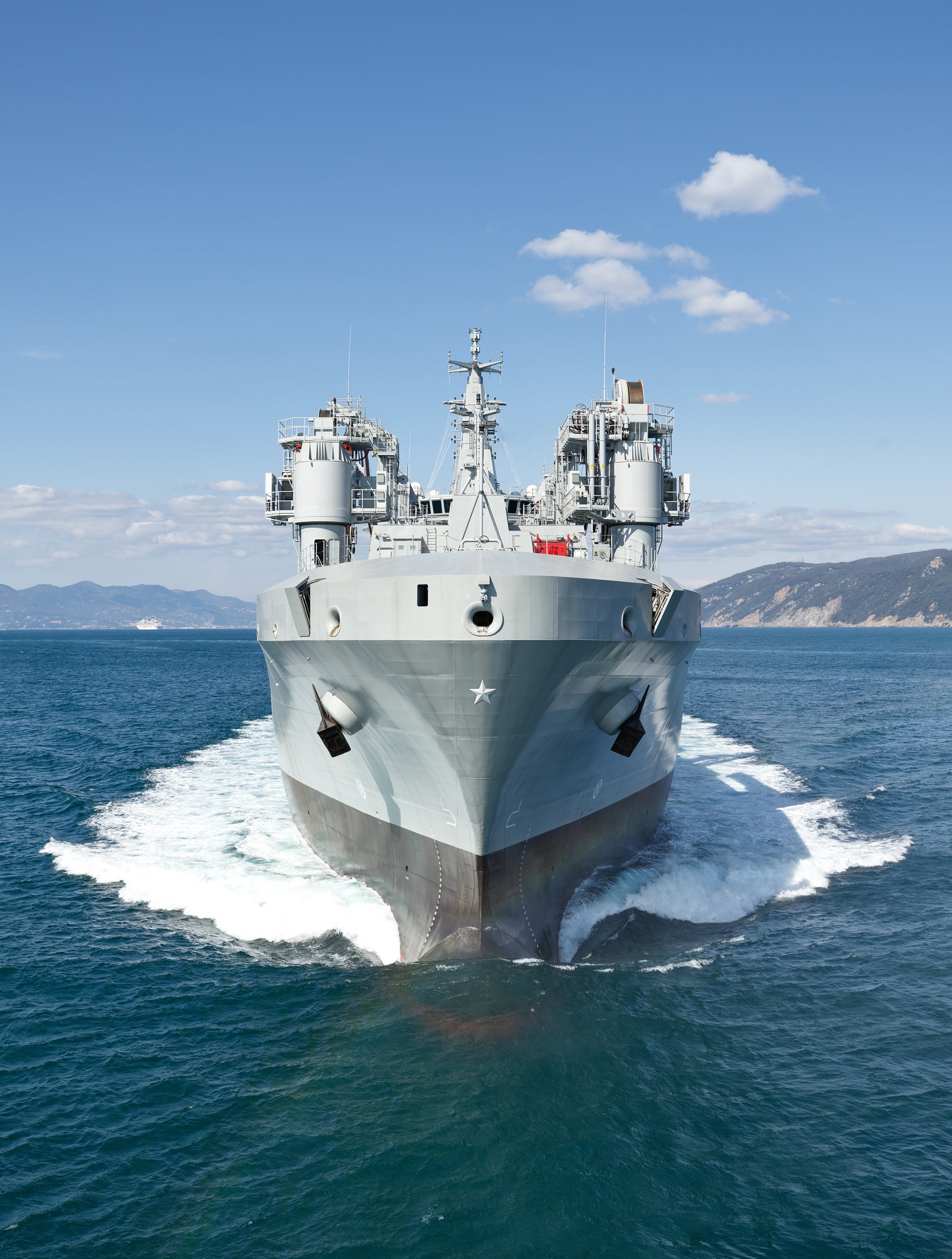 Fincantieri | Gruppo - Business - Prodotti - Navi Logistiche e di Rifornimento - Classe Vulcano: Vista frontale della nave LSS Vulcano operativa in navigazione, ambiente oceanico ampio, sfondo con montagne all’orizzonte.