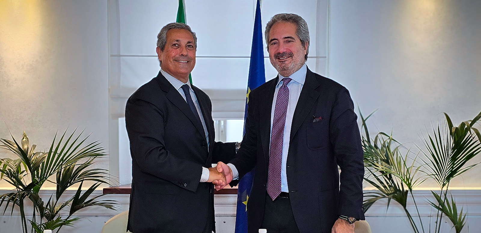 newsroom - press releases - 2025 - fincantieri group: concession for the port of ancona signed fincantieri launches the shipyard development plan: two representatives shaking hands in front of italian and eu flags, agreement signing, office context with plants.