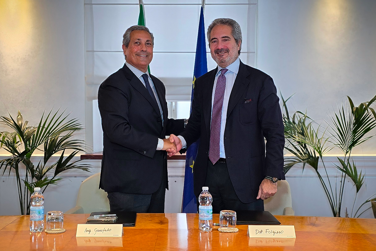 newsroom - press releases - 2025 - fincantieri group: concession for the port of ancona signed fincantieri launches the shipyard development plan: two representatives shaking hands in front of italian and eu flags, agreement signing, office context with plants.