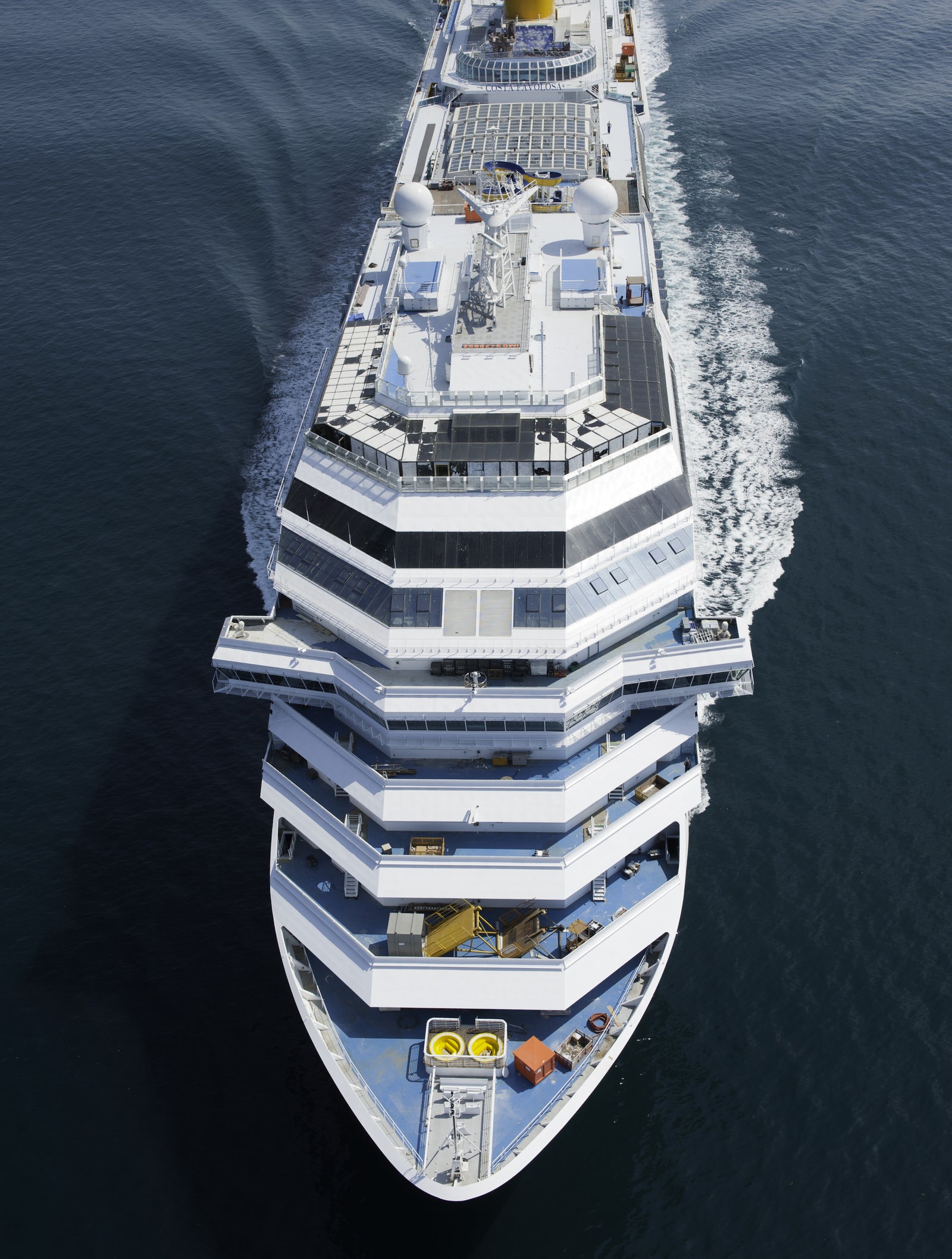  Fincantieri | Group - Business - Products - Cruise Ships - Costa Favolosa: Aerial view of large multi-deck luxury cruise ship in operation sailing through calm open waters, multiple levels with outdoor seating and recreational areas, white and blue color palette enhances serene maritime setting, design emphasizes modernity and comfort.