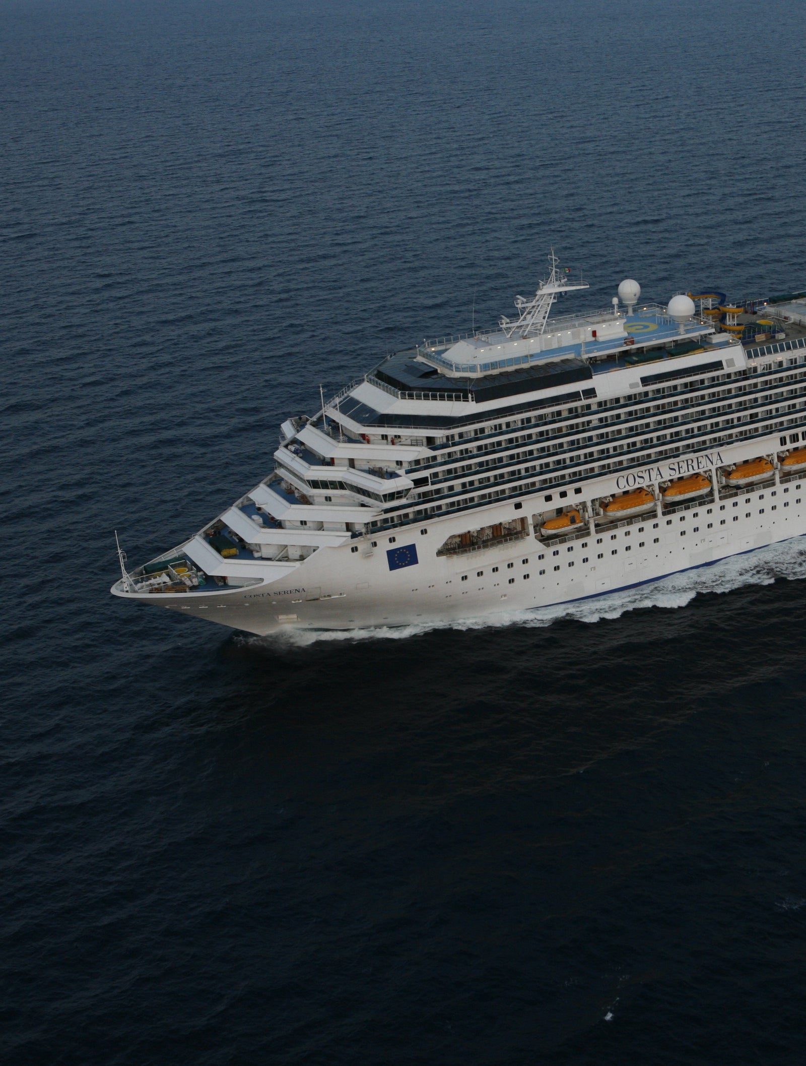 Fincantieri | Gruppo - Business - Prodotti - Navi da Crociera - Costa Pacifica: Nave da crociera bianca imponente operativa che naviga su acque calme e aperte, più ponti, camino giallo distintivo con logo 'C' visibile, scenario sereno senza altre navi o terra, evidenzia la vastità dell’oceano.