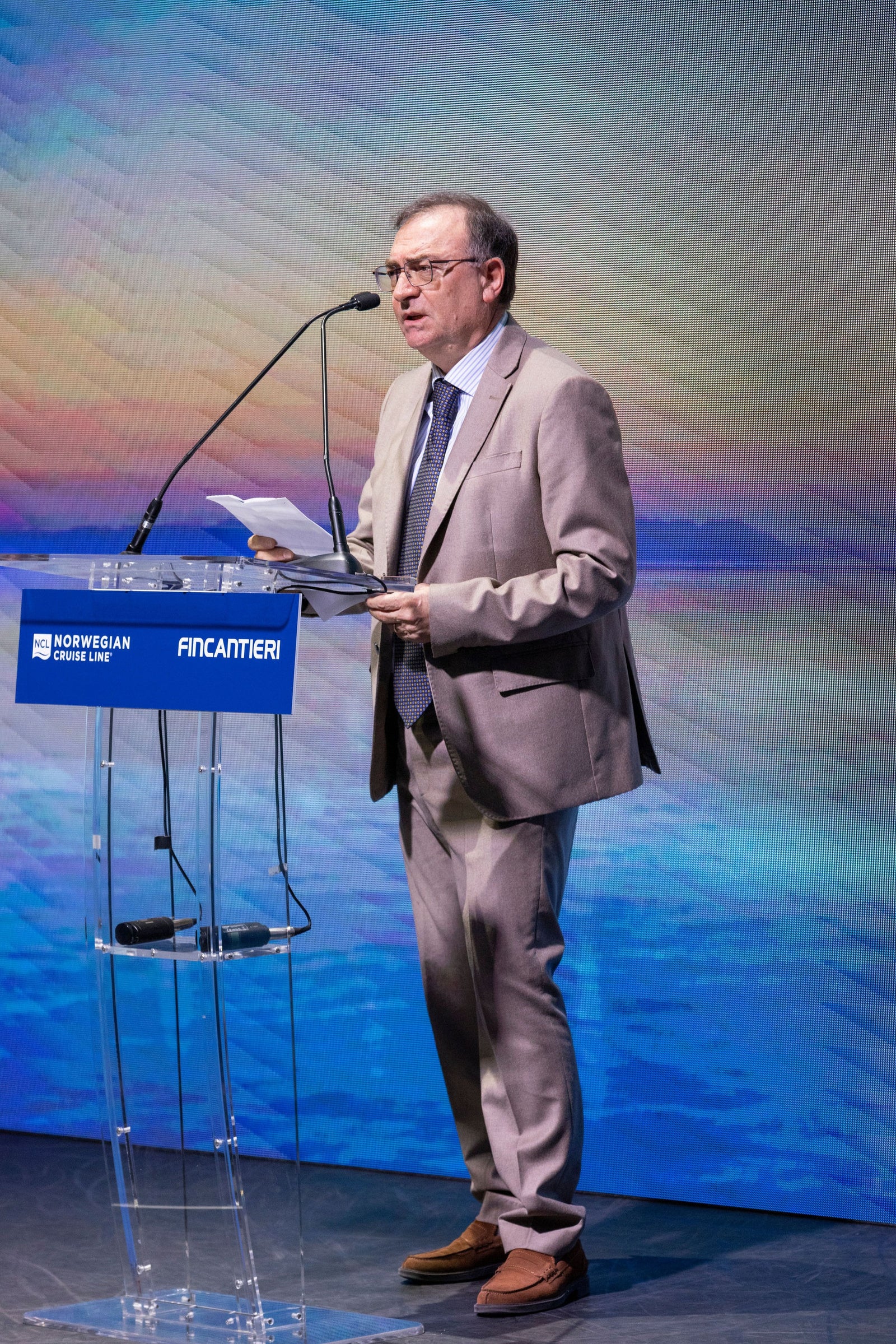 Newsroom - Press releases - 2026 - Fincantieri Group: Fincantieri delivers Norwegian Luna in Marghera: Fincantieri representative in beige suit speaks at podium with Fincantieri and Norwegian Cruise Line logos.