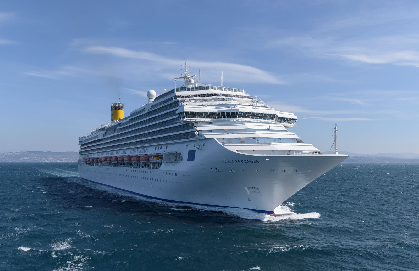 Fincantieri | Group - Business - Products - Cruise Ships - Costa Diadema: Massive white cruise ship in operation sailing through calm open waters under clear blue sky, multiple decks and visible lifeboats along sides, 'Costa Diadema' name clearly displayed on hull.