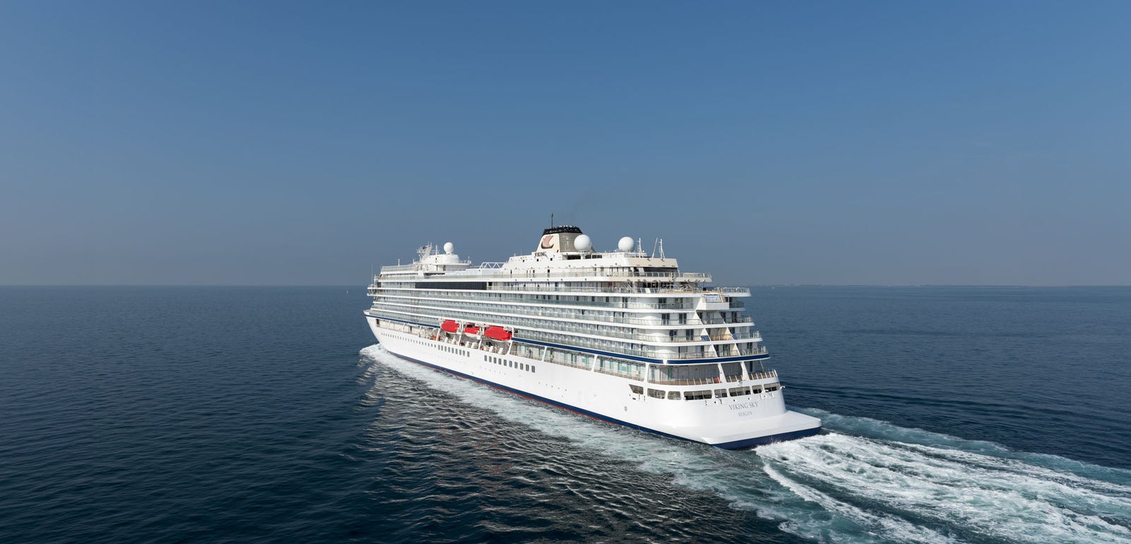 Fincantieri | Group - Business - Products - Cruise Ships - Viking Sky: Side view of Viking Sky cruise ship in operation navigating open sea, linear profile white hull, multiple passenger decks, visible lifeboats.