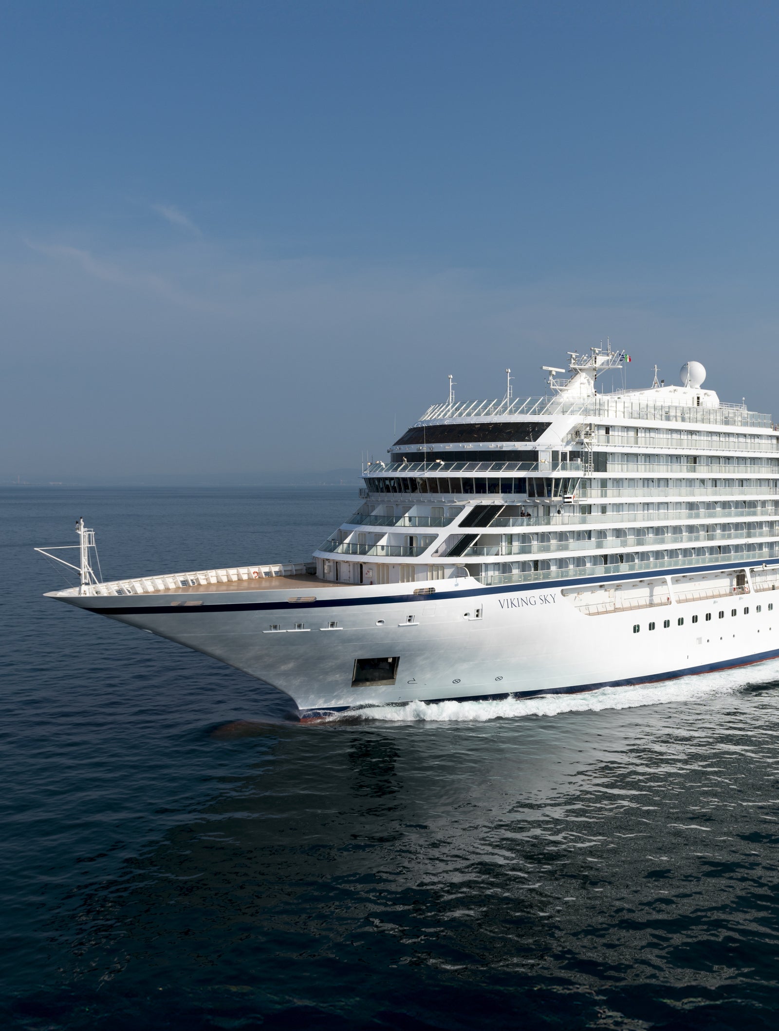 Fincantieri | Gruppo - Business - Prodotti - Navi da Crociera - Viking Star: Grande nave da crociera moderna operativa che scivola su acque oceaniche calme sotto cielo blu limpido, multipli ponti e scialuppe di salvataggio visibili, scenario che enfatizza grandezza, sicurezza e viaggio di piacere.