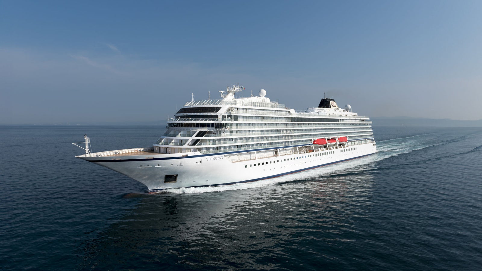 Fincantieri | Gruppo - Business - Prodotti - Navi da Crociera - Viking Star: Grande nave da crociera moderna operativa che scivola su acque oceaniche calme sotto cielo blu limpido, multipli ponti e scialuppe di salvataggio visibili, scenario che enfatizza grandezza, sicurezza e viaggio di piacere.