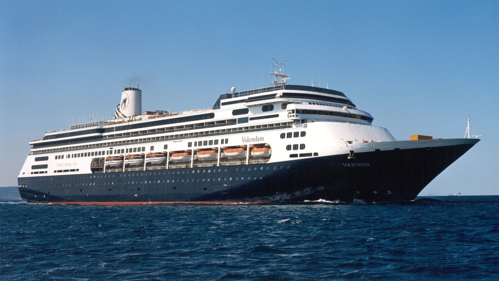 Fincantieri | Group - Business - Products - Cruise Ships - Volendam: Side view of Volendam cruise ship in operation navigating, linear hull design, multiple passenger decks, 'Volendam' name visible on bow.