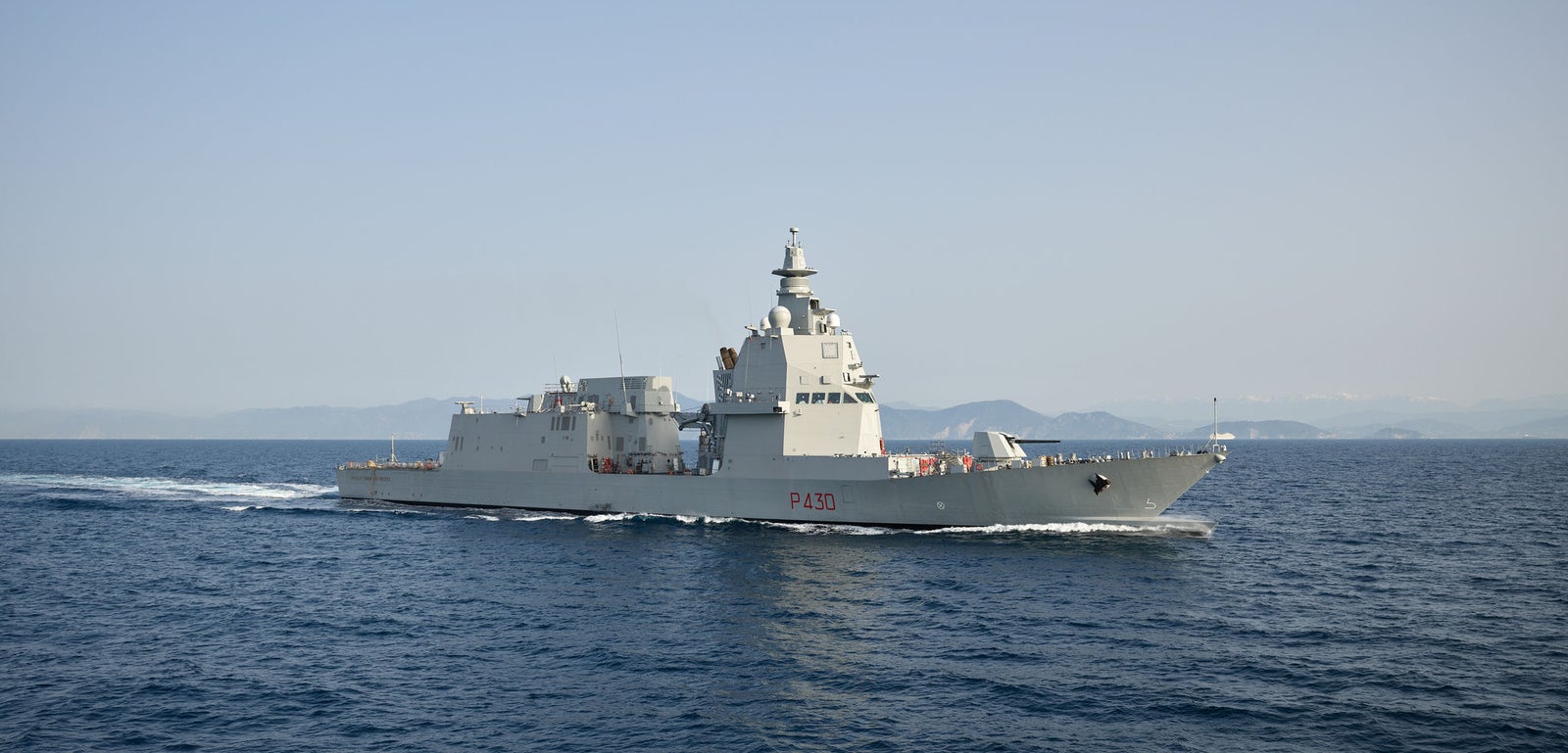  Fincantieri | Gruppo - Business - Prodotti - Navi per la difesa - Fregate - Classe Thaon de Revel: Vista laterale della nave operativa in navigazione, scafo moderno con numero P430 visibile, sfondo terre emerse distanti.