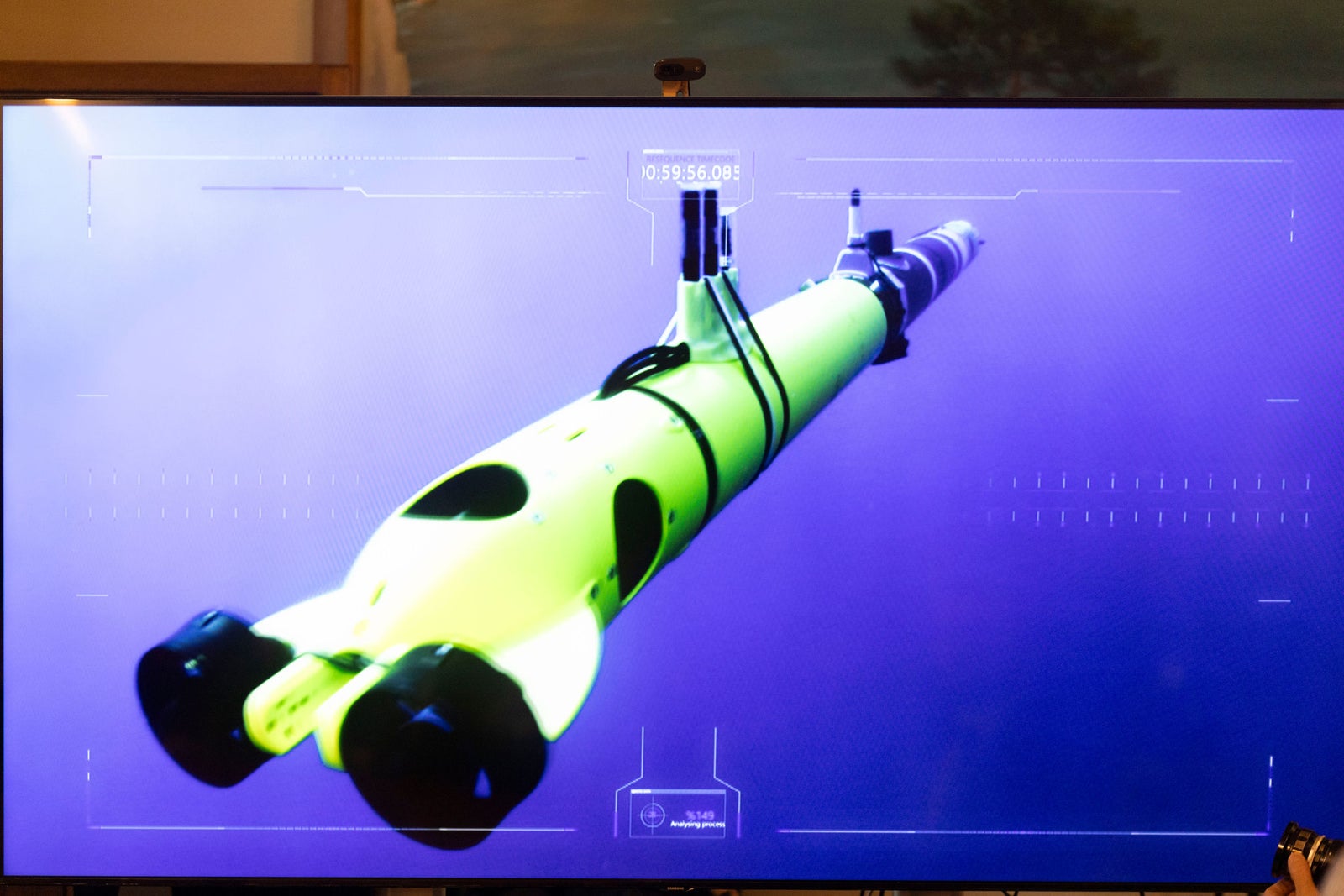 Fincantieri | Newsroom, Deep:  A bright yellow underwater drone is showcased on a digital screen with a futuristic interface overlay. The setting appears to be a technological or marine exploration environment. The drone features sleek design elements and is surrounded by a purple-toned background, emphasizing its modern aesthetic. Visible text includes 'OSSEGEN' and other interface details.