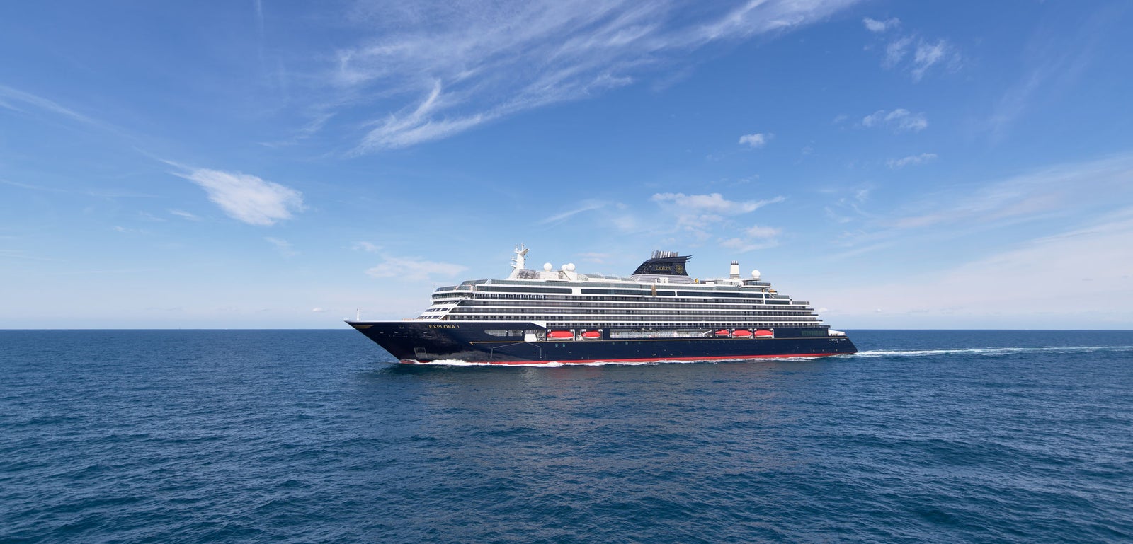 Fincantieri | Group - Business - Products - Cruise Ships - Explora I: Side view of luxury cruise ship in operation, black hull with white and red details, Explora Journeys branding visible.