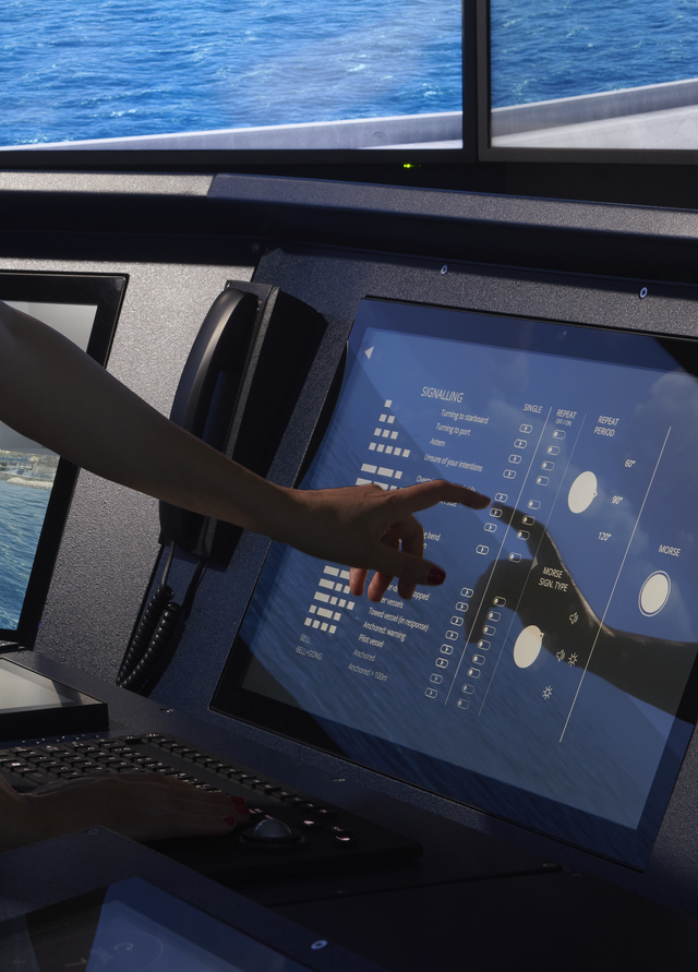Fincantieri | Innovazione: Una donna utilizza un simulatore navale, controllando i sistemi della nave simulata tramite un touch screen. Grandi schermi alle sue spalle mostrano una vista realistica dell’oceano, offrendo una simulazione visiva.