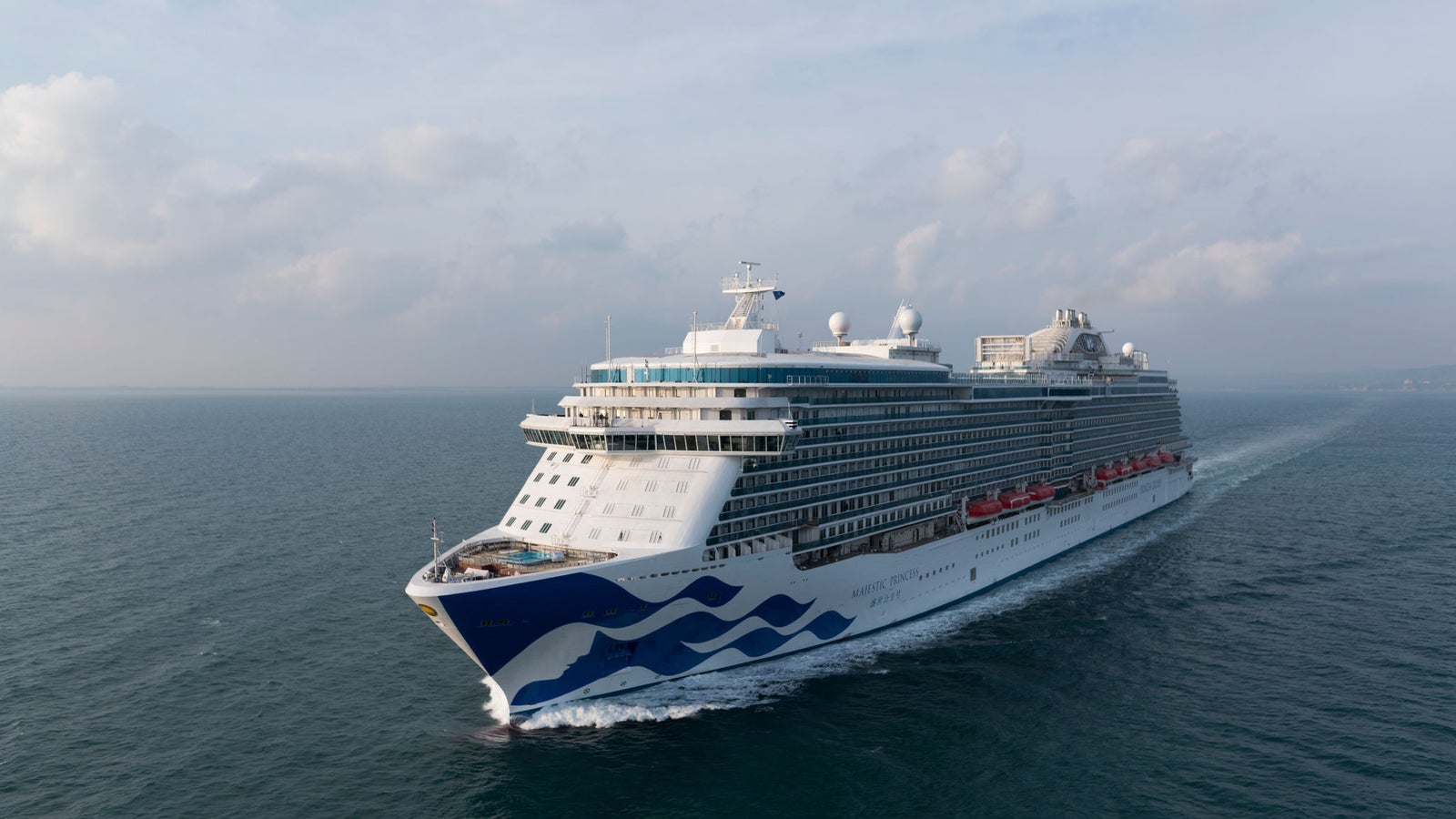 Fincantieri | Group - Business - Products - Cruise Ships - Majestic Princess: Large operational luxury cruise ship sailing on calm ocean waters under partly cloudy sky, wave design on hull and multiple decks with visible amenities.