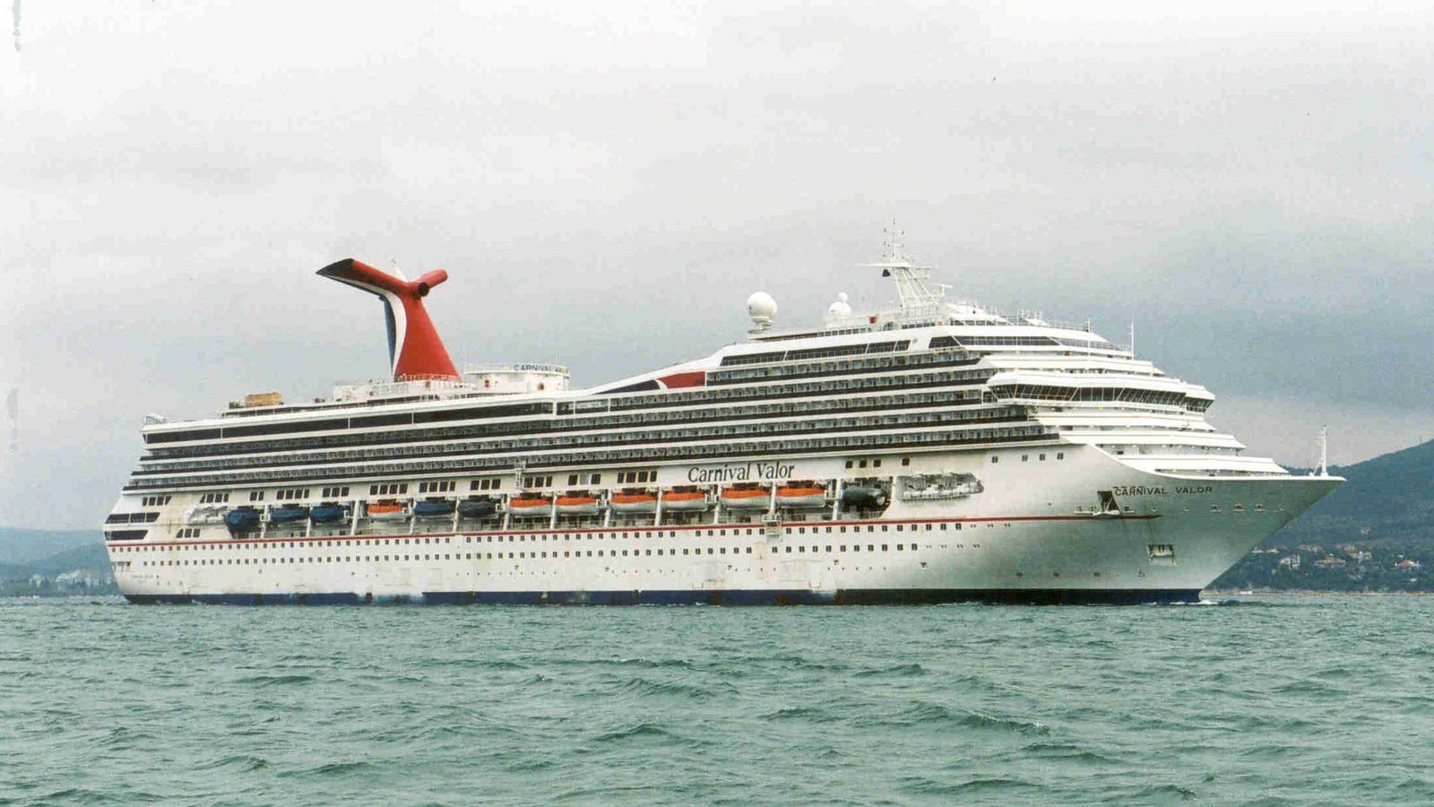  Fincantieri | Gruppo - Business - Prodotti - Navi da Crociera - Carnival Valor: Vista laterale della nave Carnival Valor operativa in navigazione, scafo con ponti multipli e fumaiolo rosso a forma di ala.