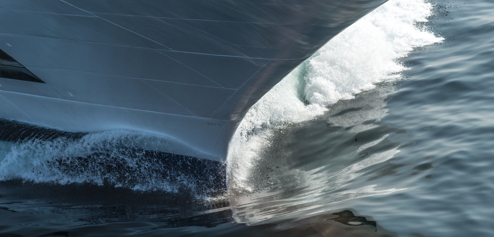 Fincantieri | Group - Business - Products - Cruise Ships - Viking Sky: Close-up of Viking Sky cruise ship bow in operation cutting through water with spray, navigating open sea, linear profile hull.